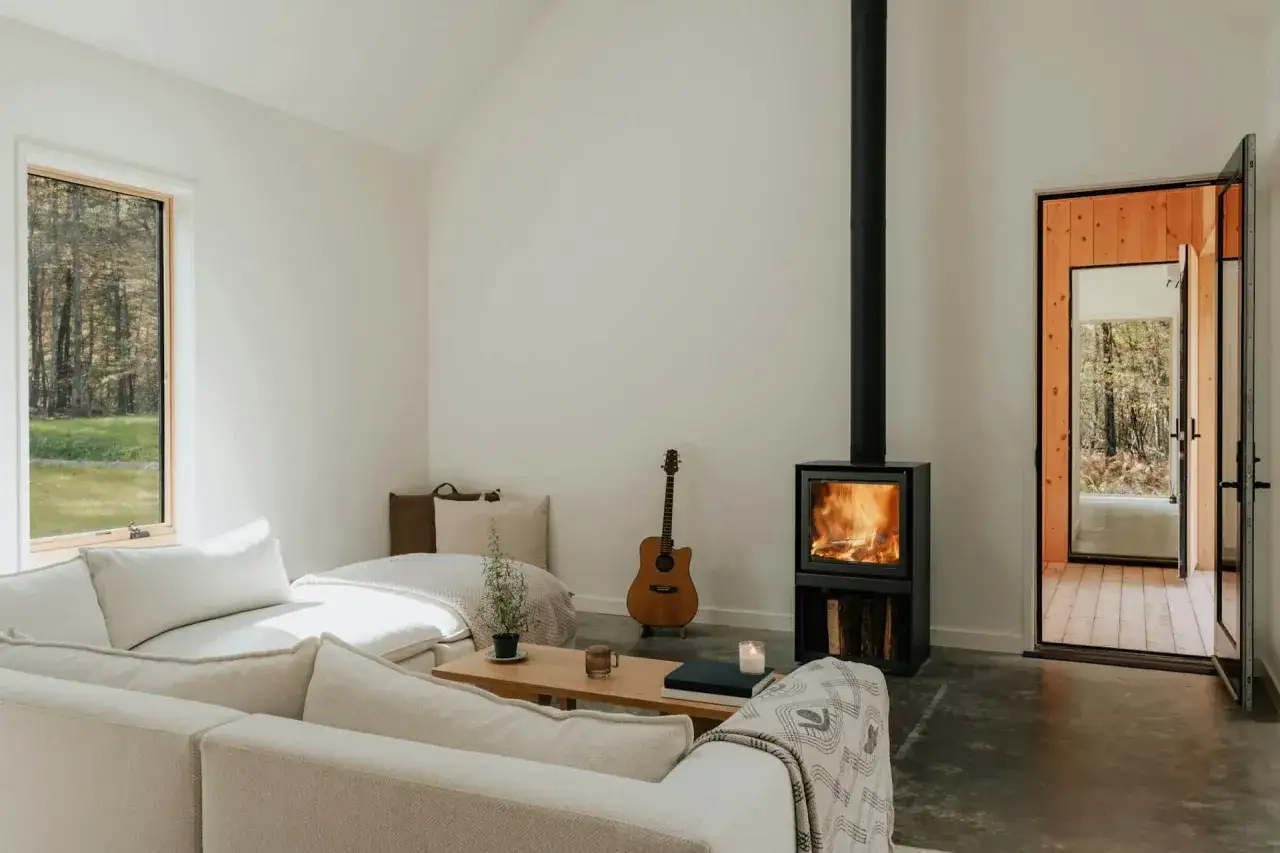 Salon cosy avec poêle à bois allumé, guitare et canapé. Idéal pour une aide financière tubage cheminée.