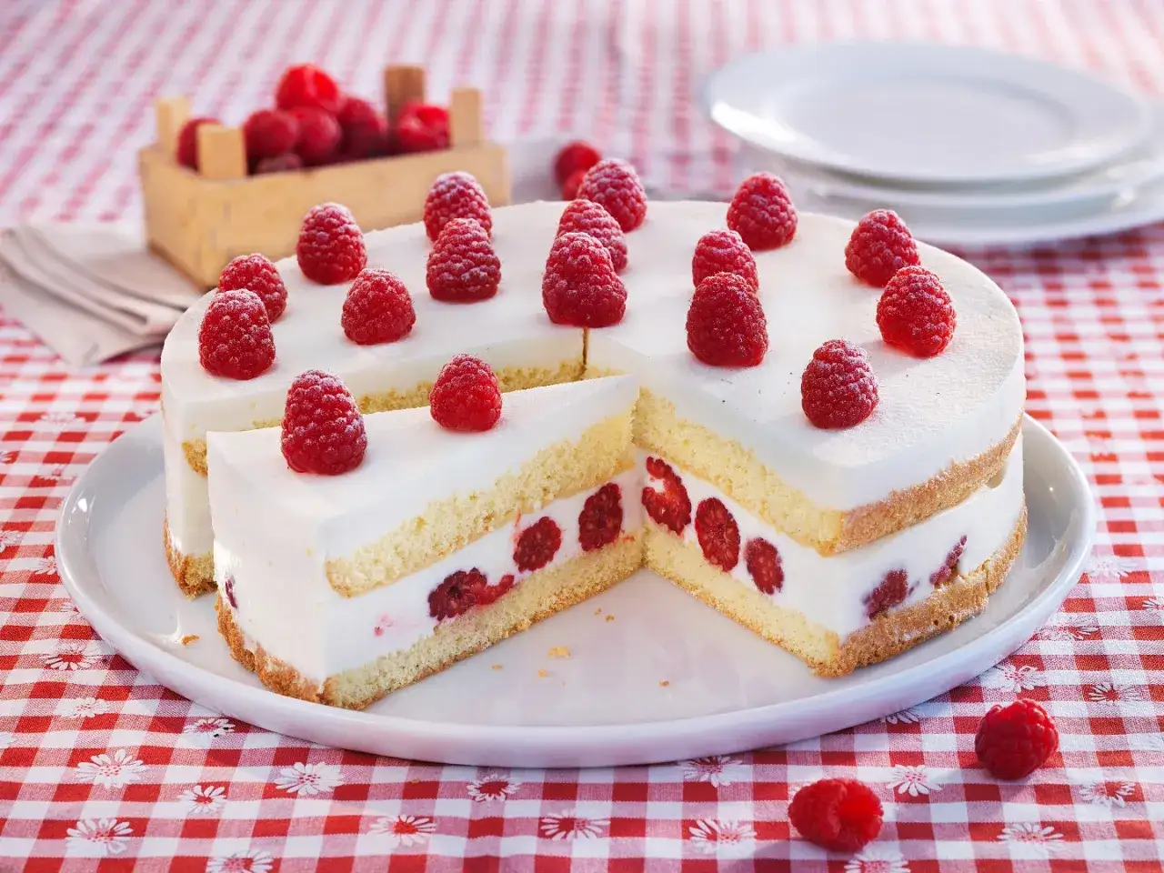 Leckere joghurt-torte mit biskuitboden und frischen Himbeeren, verziert mit weiteren Himbeeren.