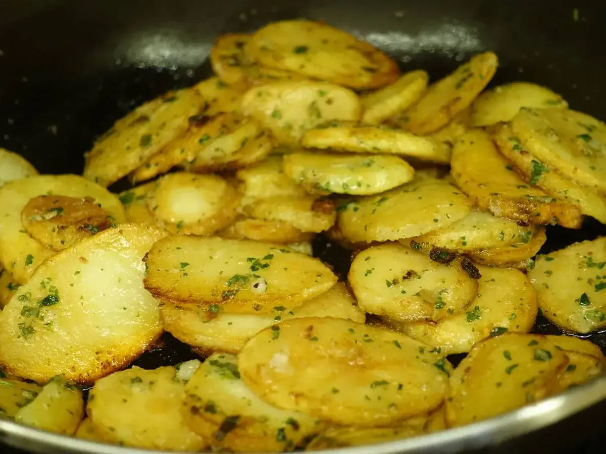 Patatas panaderas al horno crujientes, doradas y con perejil picado, listas para disfrutar.