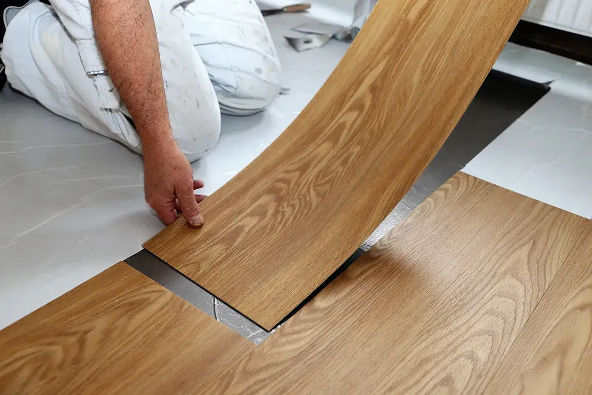 Ein Handwerker verlegt Laminat. Die Frage, wie dick ist Laminat, wird hier durch die sichtbare Kante der Diele beantwortet.