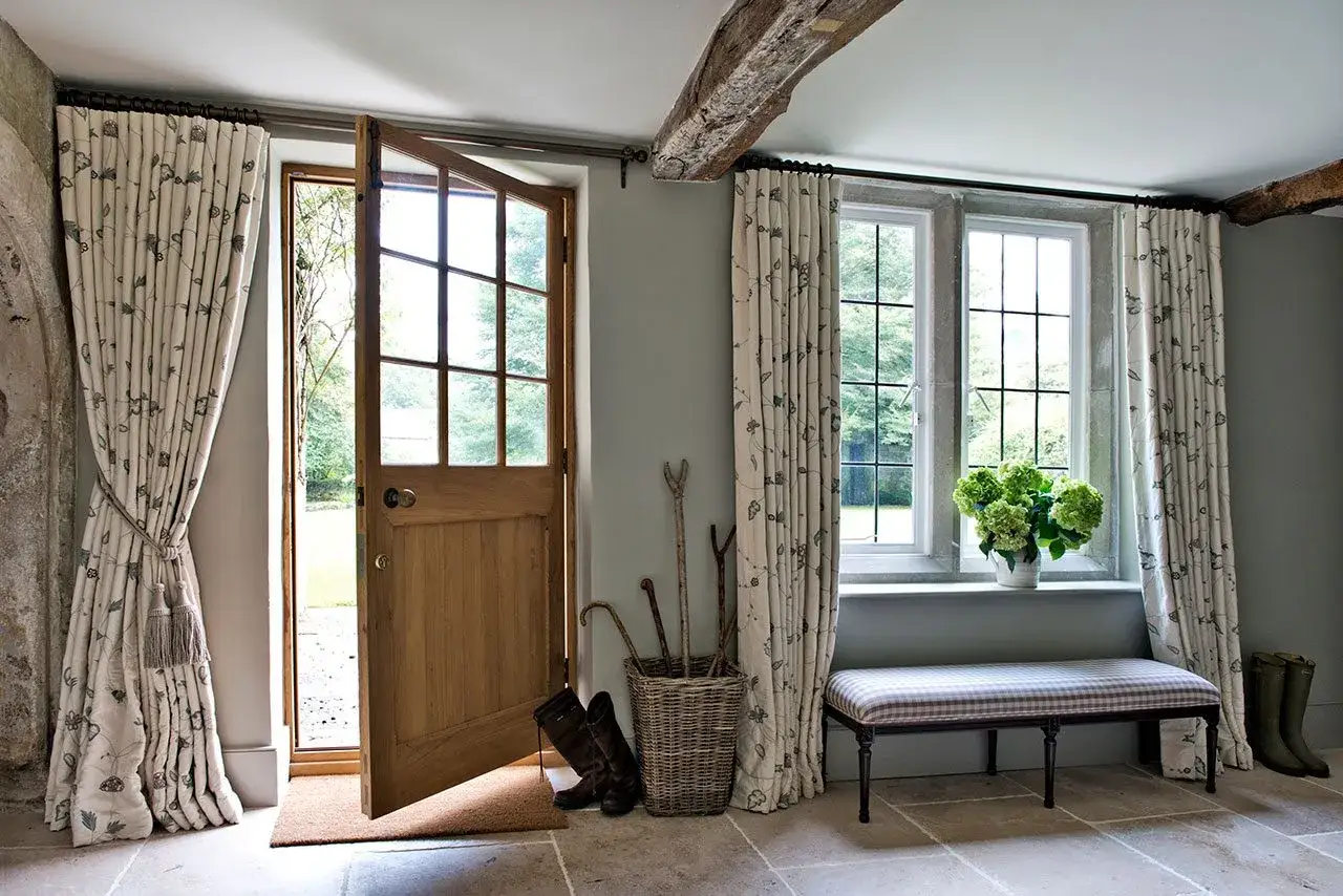 Landhaus-Flair mit floralen Gardinen-Ideen: Ein offenes Holztor, Stiefel und ein Korb mit Wanderstöcken schaffen Gemütlichkeit.