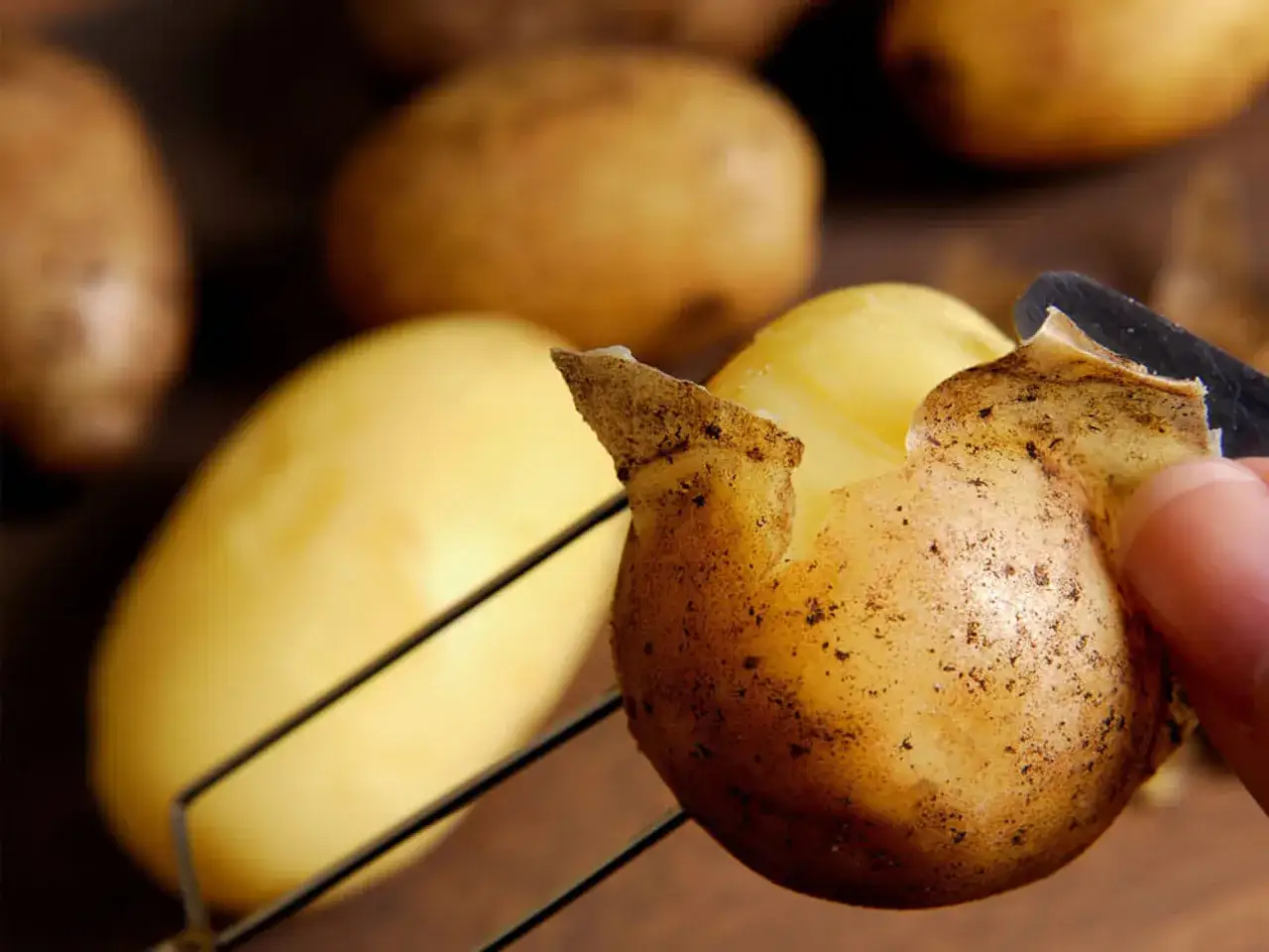 Frische Kartoffeln werden gesch&auml;lt, um sie mit Schale zu essen.