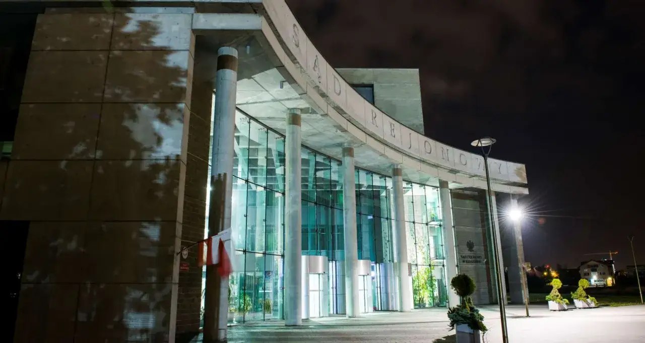 Nowoczesny budynek sądu w Rzeszowie nocą, z napisem 