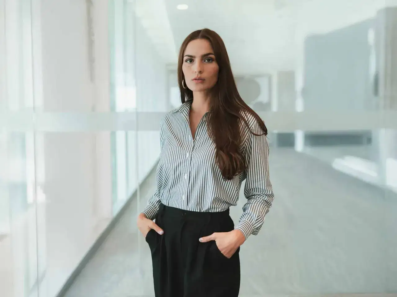 Frau in gestreifter Bluse und schwarzen Hosen, ein schick-l&auml;ssiges Outfit f&uuml;r den B&uuml;roalltag.