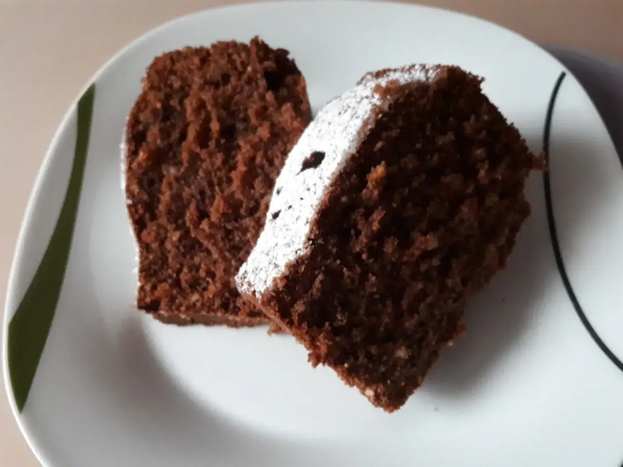 Zwei saftige St&uuml;cke Schokoladenkuchen, ein k&ouml;stlicher Kuchen ohne Mehl, best&auml;ubt mit Puderzucker auf einem wei&szlig;en Teller.