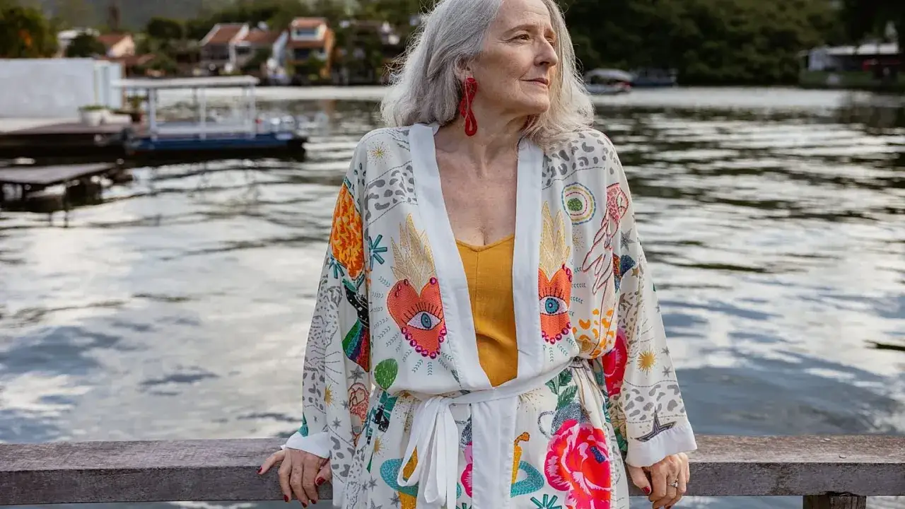 Une femme d'âge mûr, profitant de son voyage en solo à 60 ans, porte un kimono coloré au bord de l'eau.