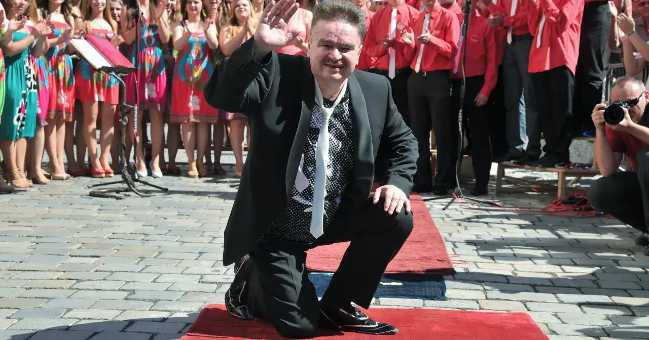 Bartłomiej Korda, syn Wojciecha Kordy, wita publiczność, klęcząc na czerwonym dywanie.
