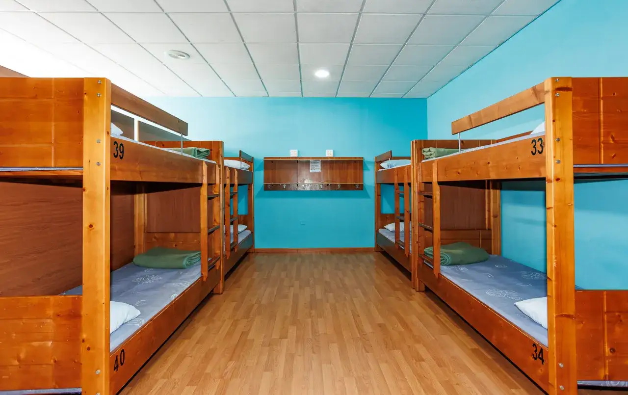 Dormitorio con literas de madera, típico de los albergues del Camino de Santiago. Cada cama está numerada y preparada para peregrinos.