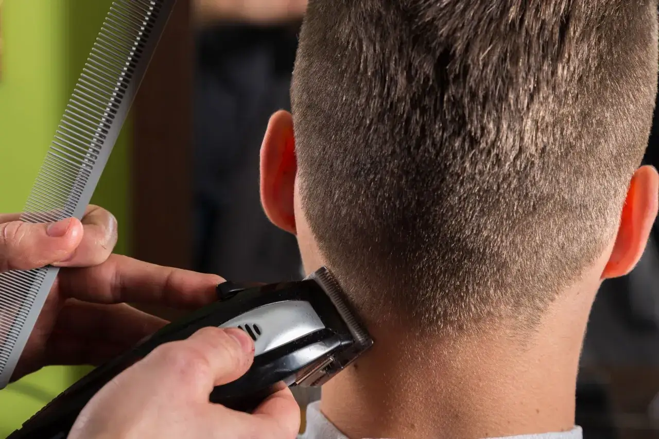Präzise Konturen Haare werden mit einem Trimmer und Kamm am Hinterkopf eines Mannes nachgearbeitet.
