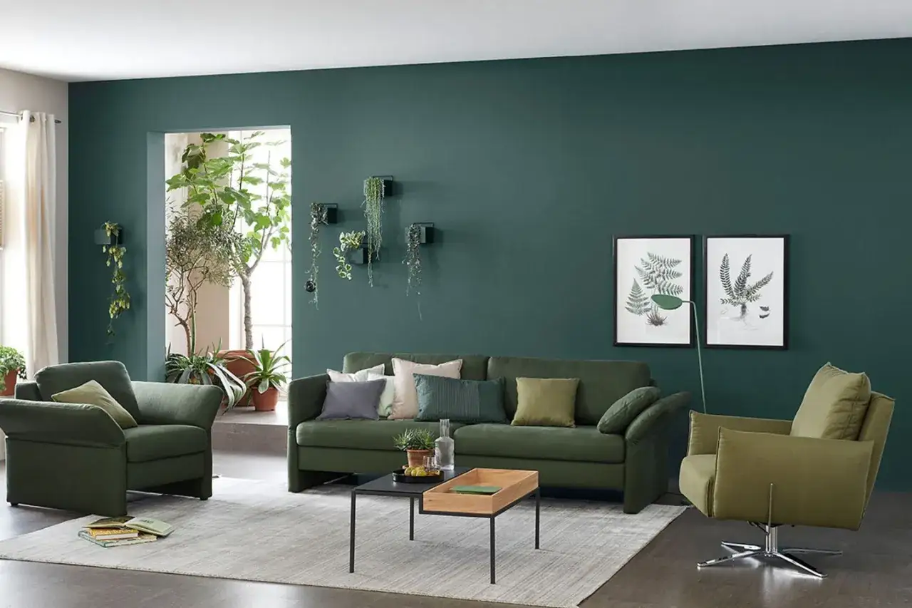 Grüne **Farben** dominieren diese **Wohnung**: Sofas, Sessel und die Wand schaffen eine beruhigende Oase. Pflanzen bringen zusätzliches Grün.