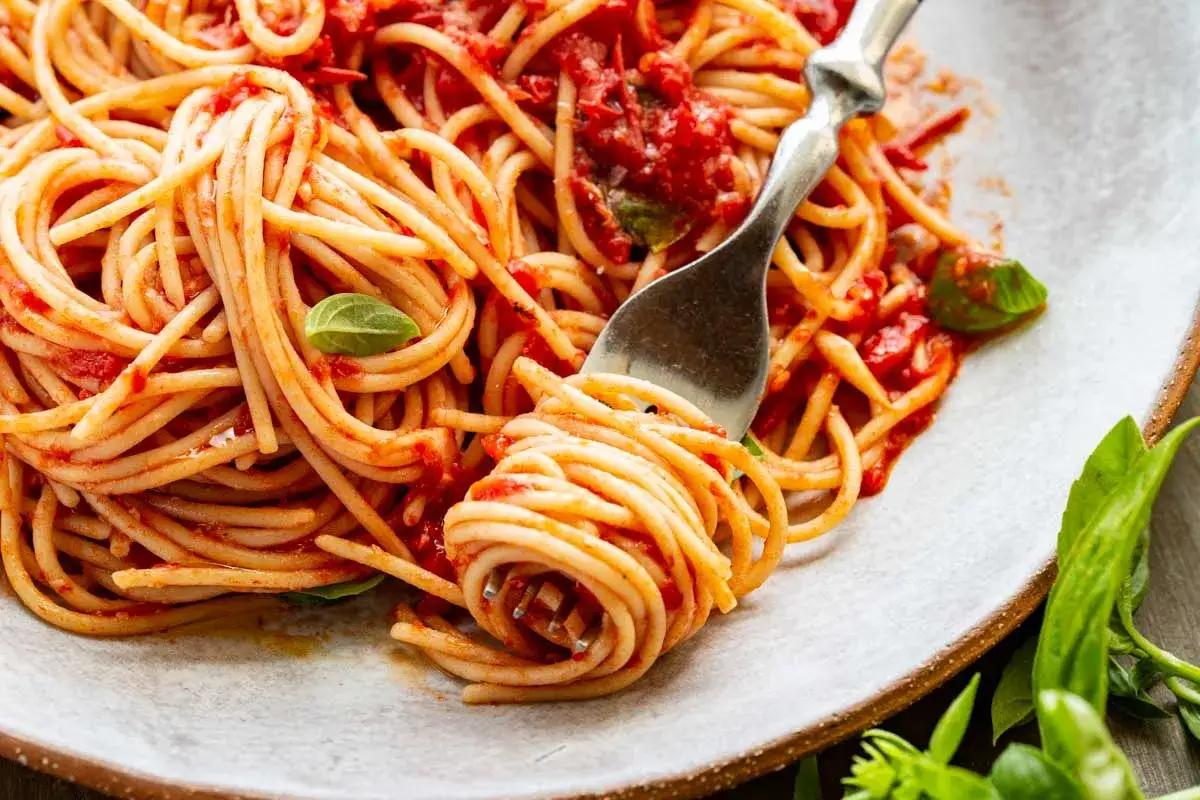 En gaffel snurrar upp en gener&ouml;s portion pasta pomodoro, t&auml;ckt av en rik tomats&aring;s och garnerad med f&auml;rsk basilika.