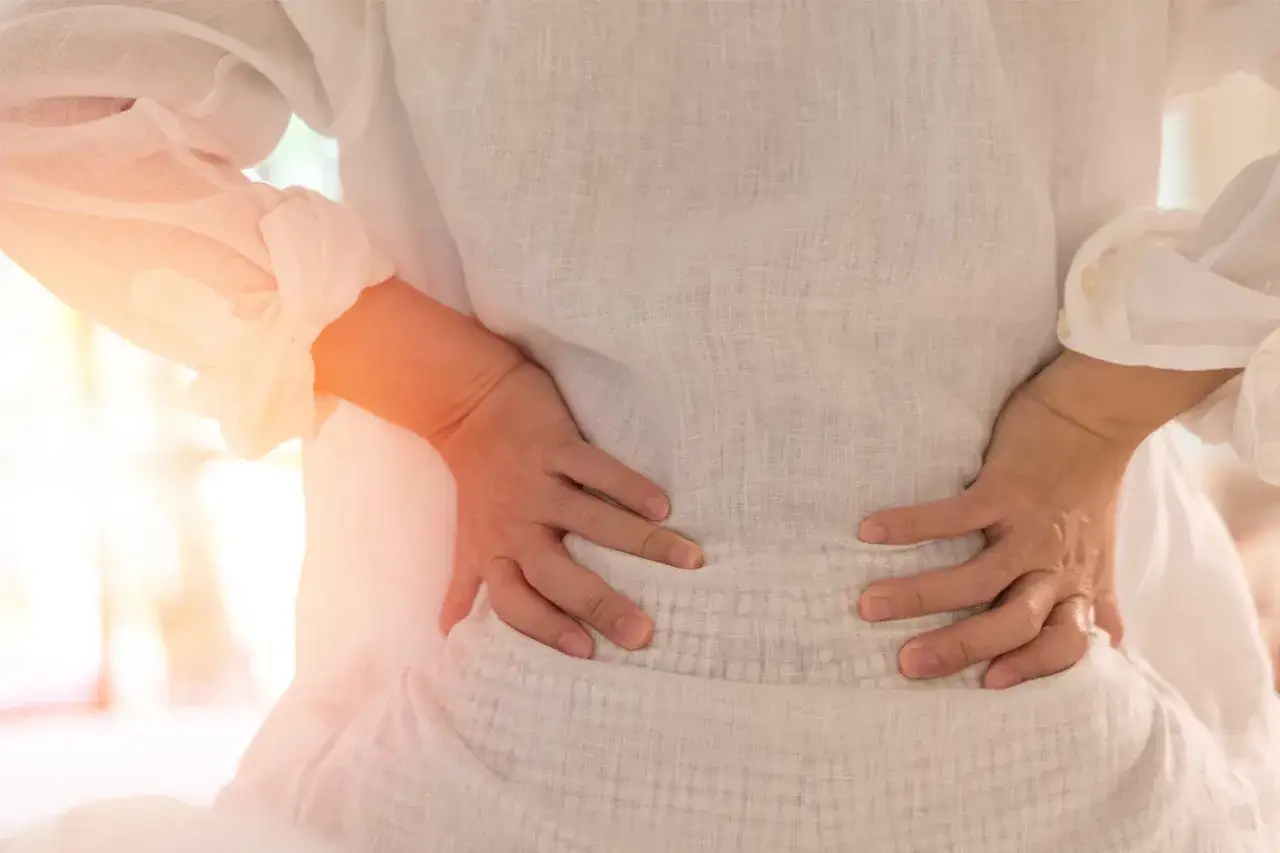 Gravid kvinna med händerna på ryggen, som visar ont i leder.