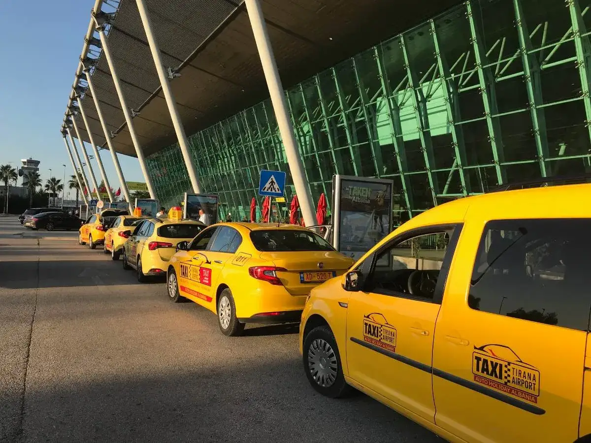 Gelbe Taxis stehen in einer Reihe vor dem modernen Flughafenterminal in Albanien.