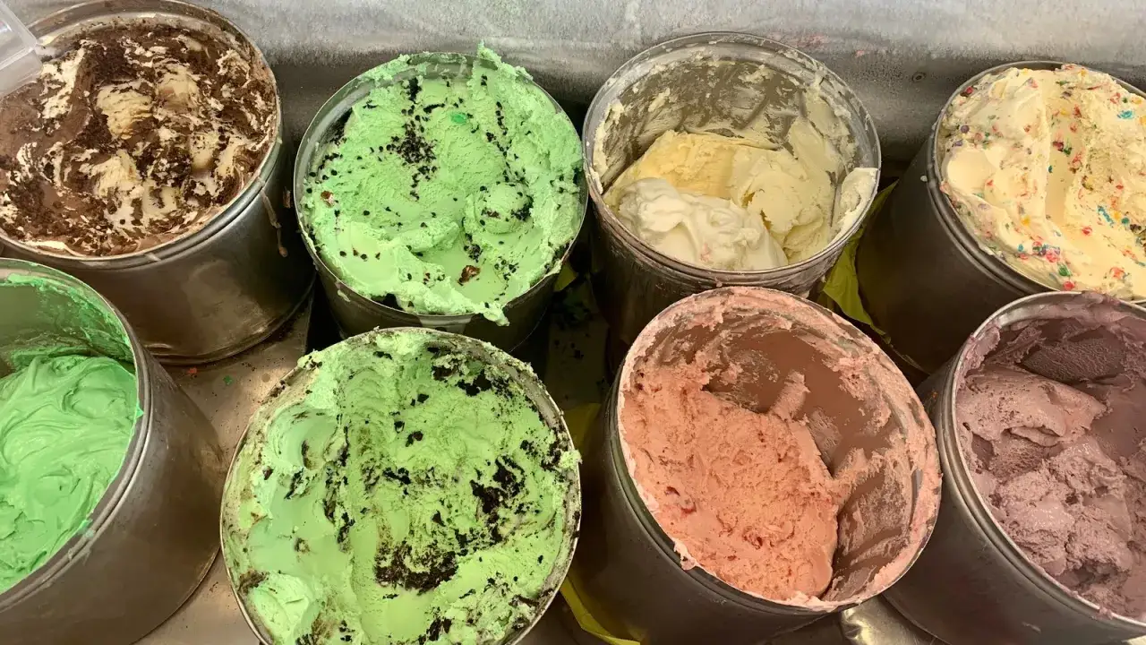 Viele Behälter mit cremigem, altem Eis in verschiedenen Farben und Geschmacksrichtungen: Schokolade, Minze, Vanille, Erdbeer und Lavendel.