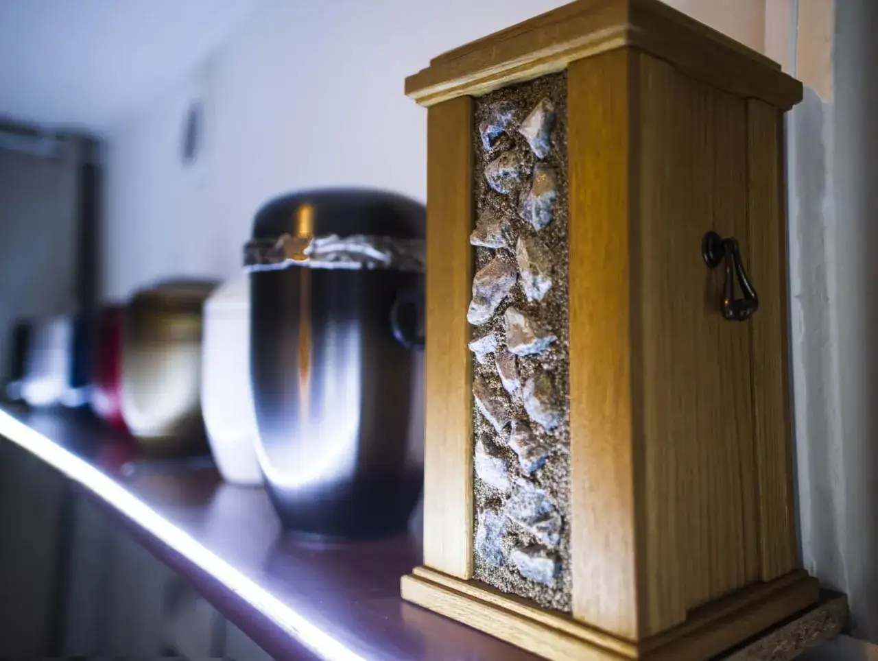 Urzna z kamieniami i piaskiem, obok innych urn. Szukasz informacji, gdzie jest najbliższe krematorium?