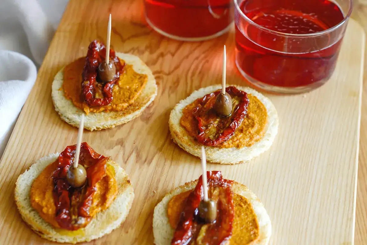 Bruschette con pat&egrave; di olive, pomodori secchi e un'oliva, perfette per un aperitivo. Ecco come si fa il pat&egrave; di olive!