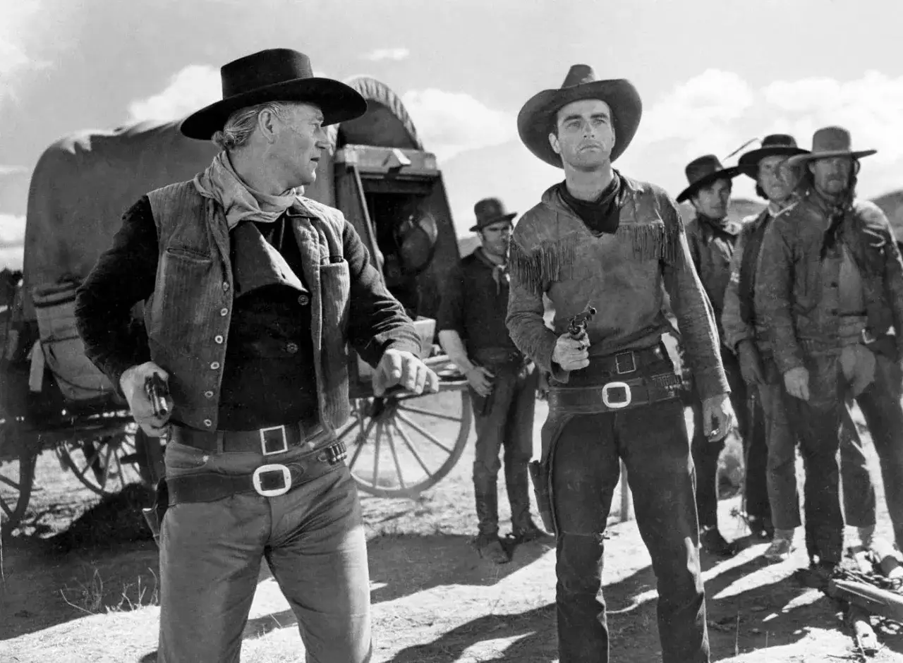 Rio Bravo obsada: John Wayne i Montgomery Clift w westernowych strojach, z rewolwerami w dłoniach, gotowi do akcji.