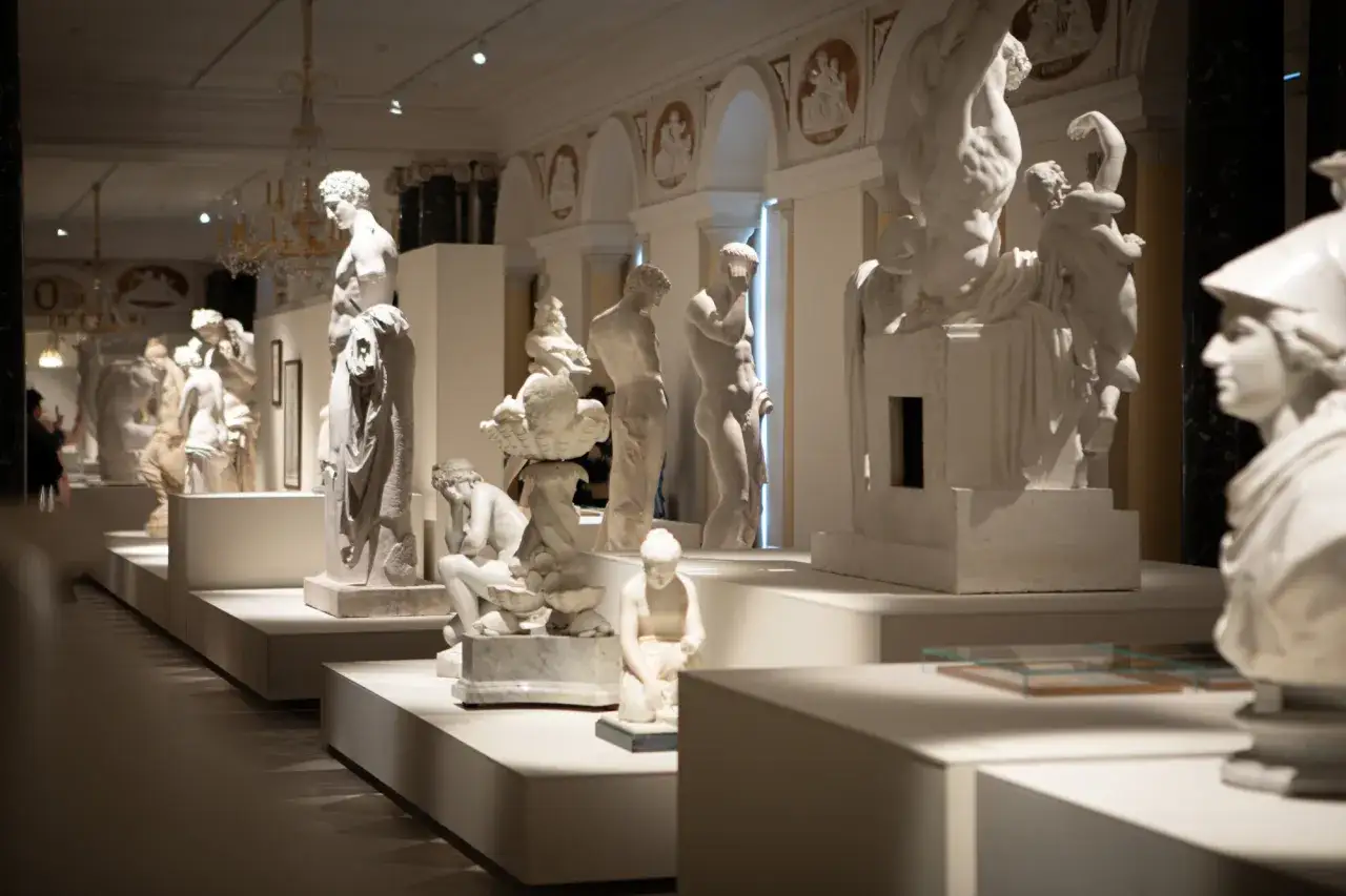 Wystawa rzeźb w muzeum interaktywnym w Warszawie. Marmurowe figury ludzi i mitologicznych stworzeń na białych postumentach.