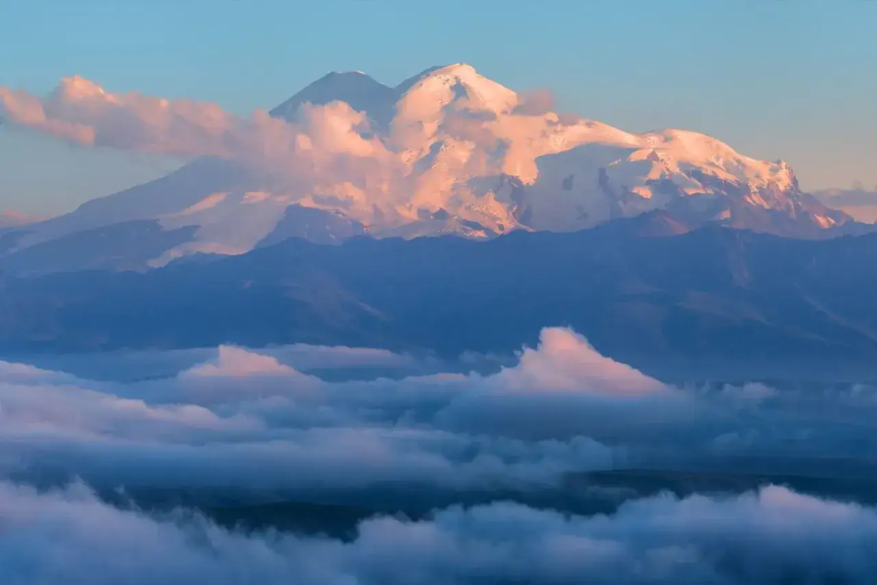 Elbrus, najwyższy szczyt Rosji, w blasku wschodzącego słońca, otoczony morzem chmur.