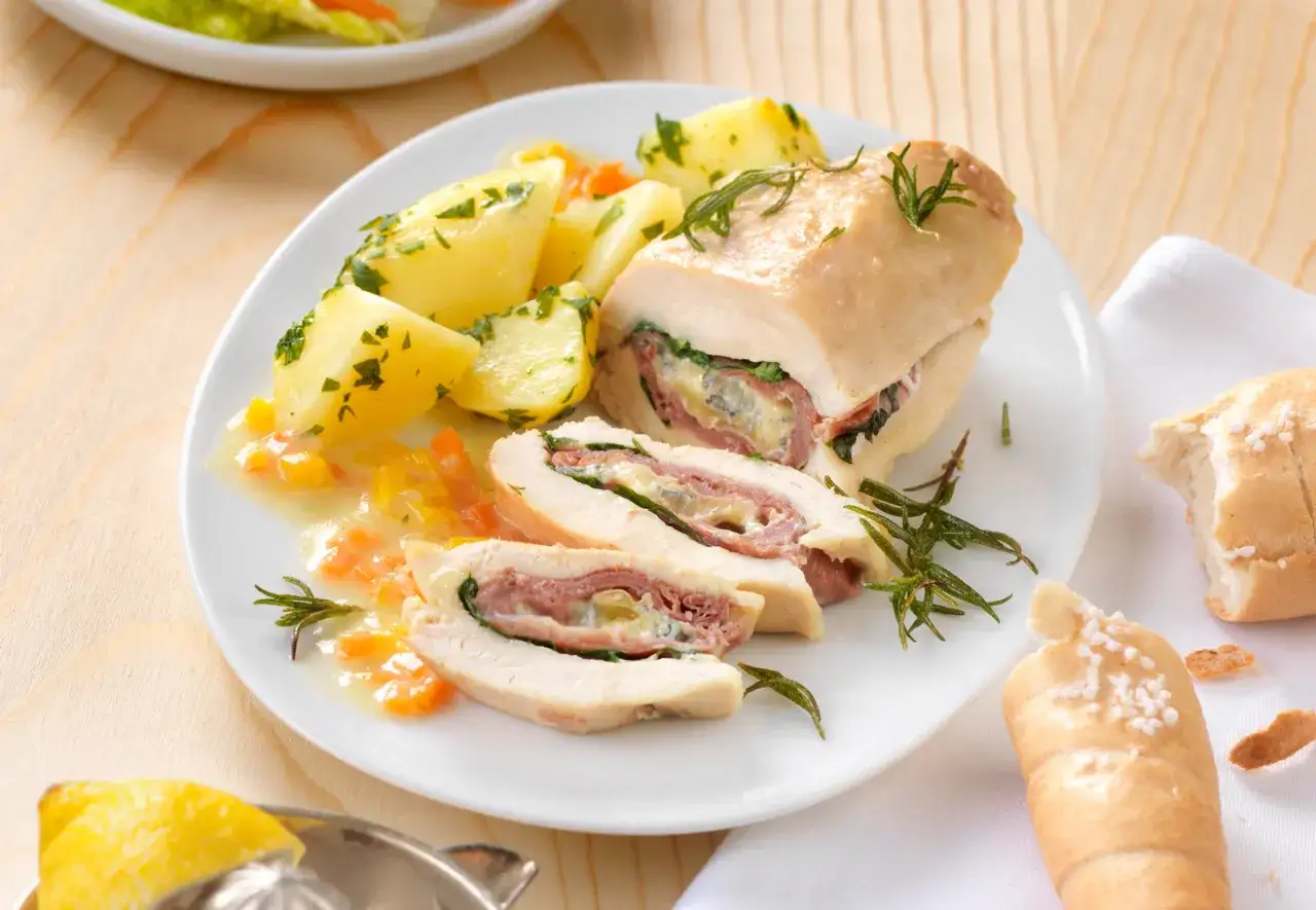 Ein saftiges Cordon Rouge mit Schinken und Käse, serviert mit Kartoffeln und einer Zitronenspalte.