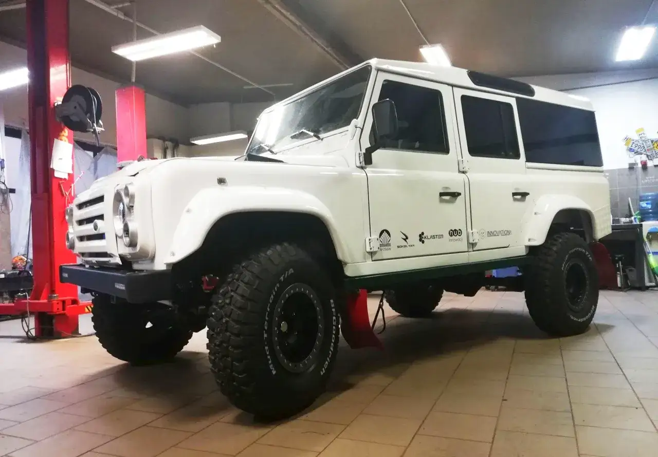 Biały Land Rover Defender, prawdziwy mhero, gotowy na terenowe wyzwania.
