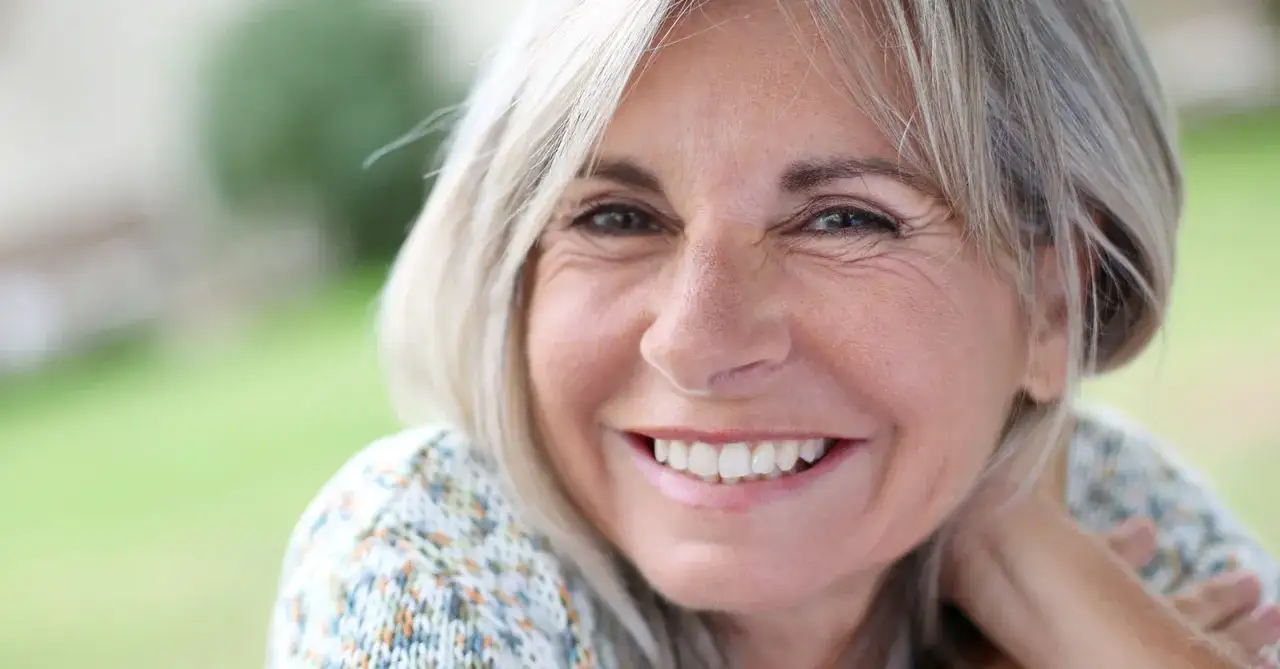 Mujer sonriente con piel radiante, un ejemplo de como cuidar la piel de la cara a los 50.