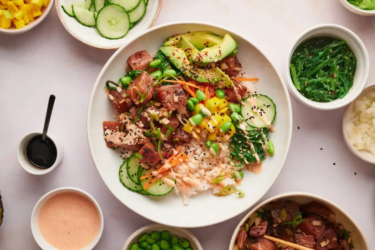 En färgglad poke bowl med ris, rå tonfisk, avokado, mango, edamamebönor och gurka. Serveras med sojasås och en krämig dressing.