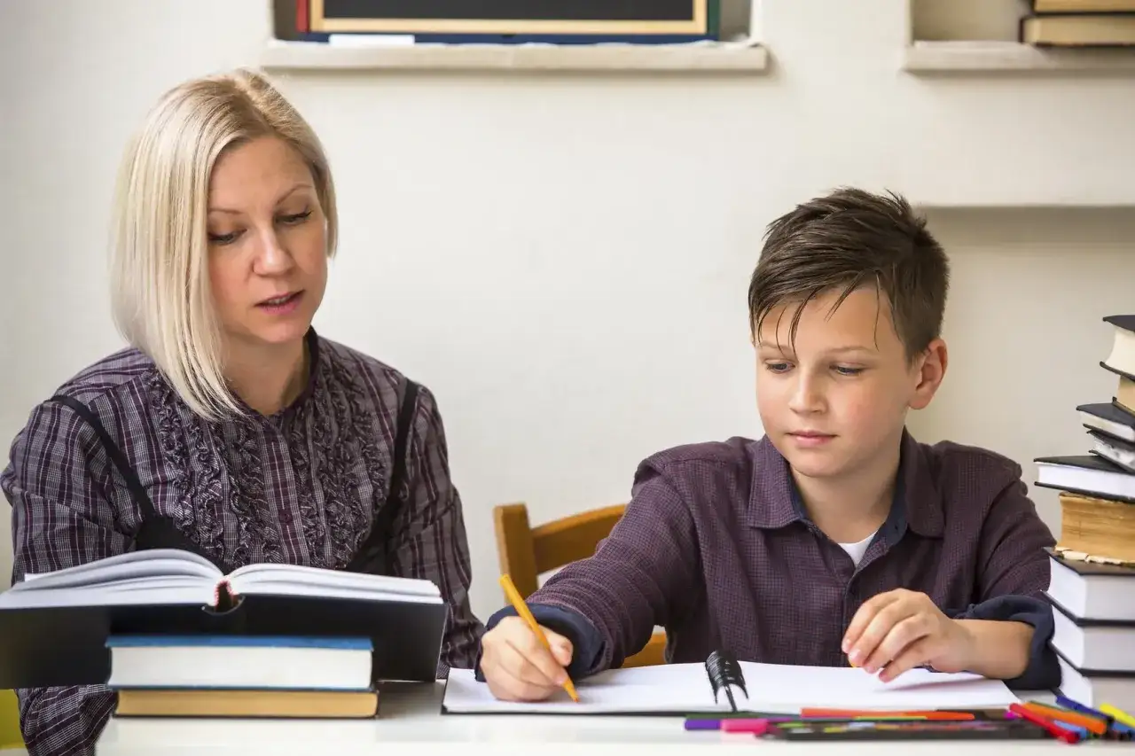 Kobieta tłumaczy chłopcu, jak działa edukacja domowa na przykładzie nauki z książek.