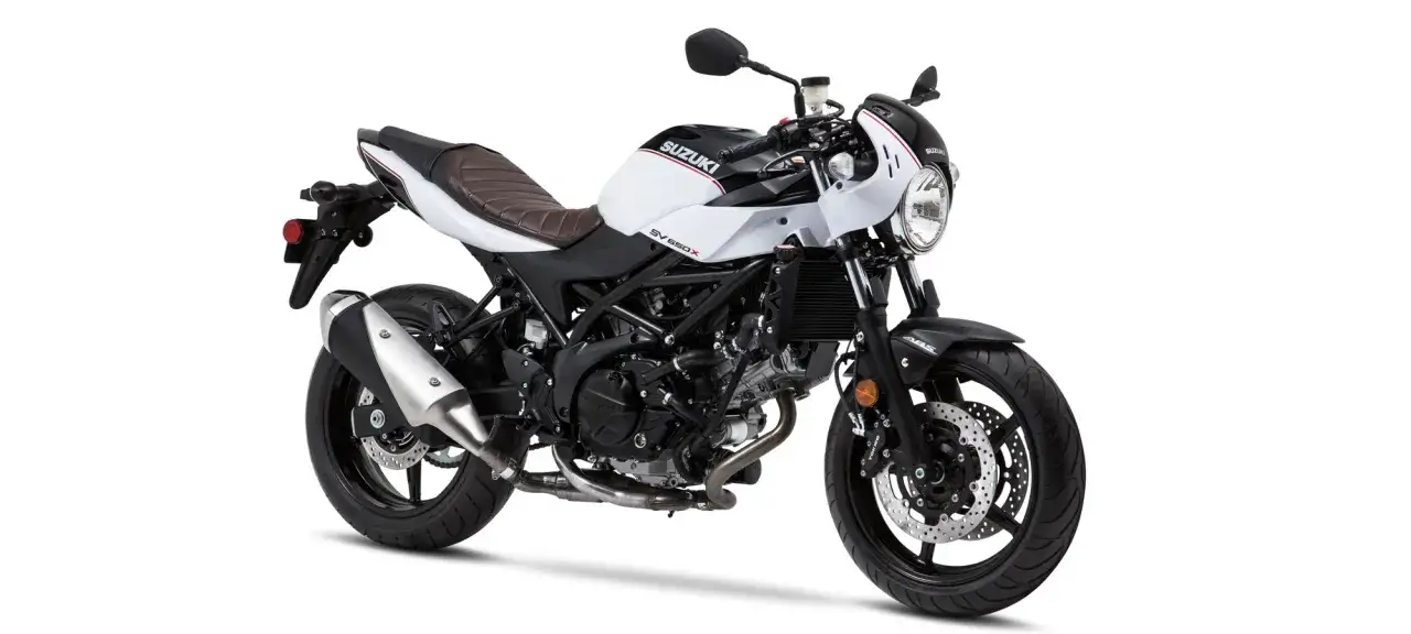 Stylowy motocykl Suzuki SV650X w kolorze białym z czarnymi akcentami i brązową kanapą, gotowy na miejskie przygody.