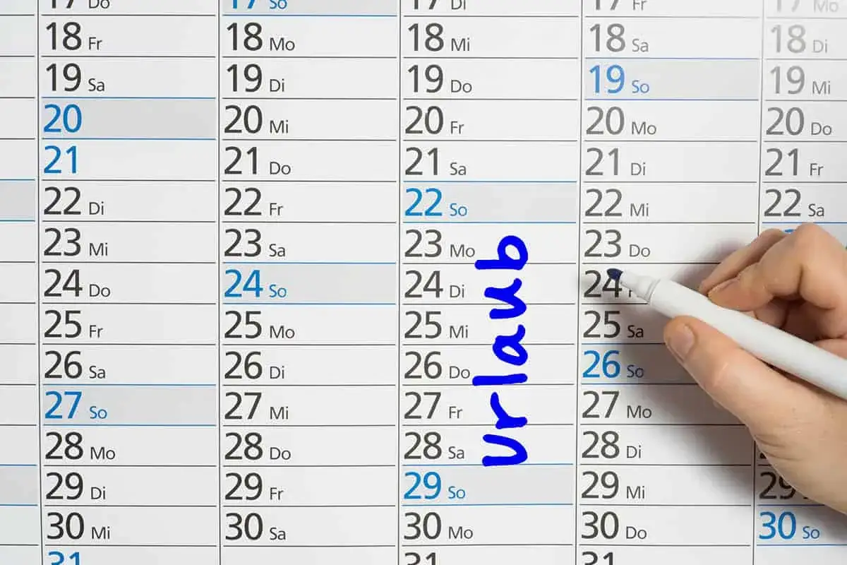 Kalenderblatt mit markierten Urlaubstagen. Ein Finger markiert den 24. mit einem Stift, während