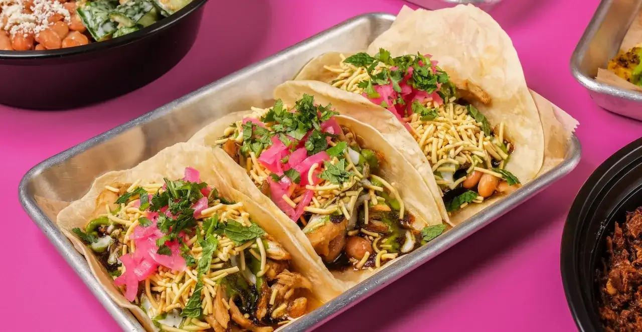 Tre l&auml;ckra asiatiska tacos med picklad r&ouml;dl&ouml;k, koriander och krispiga nudlar p&aring; ett fat.