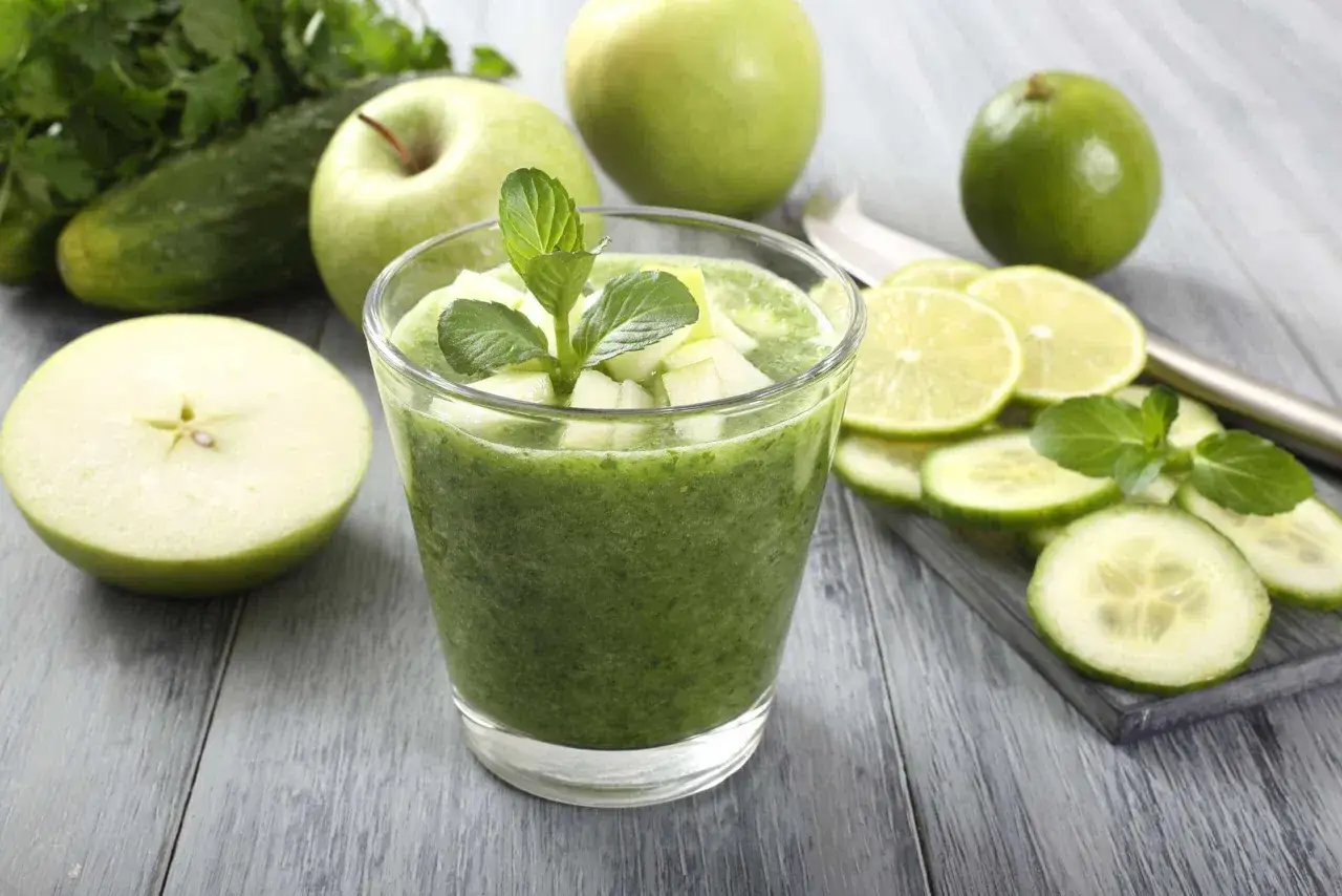 Un bicchiere di centrifugati per dimagrire, con mele verdi, cetrioli, lime e menta. Ingredienti freschi per un benessere naturale.