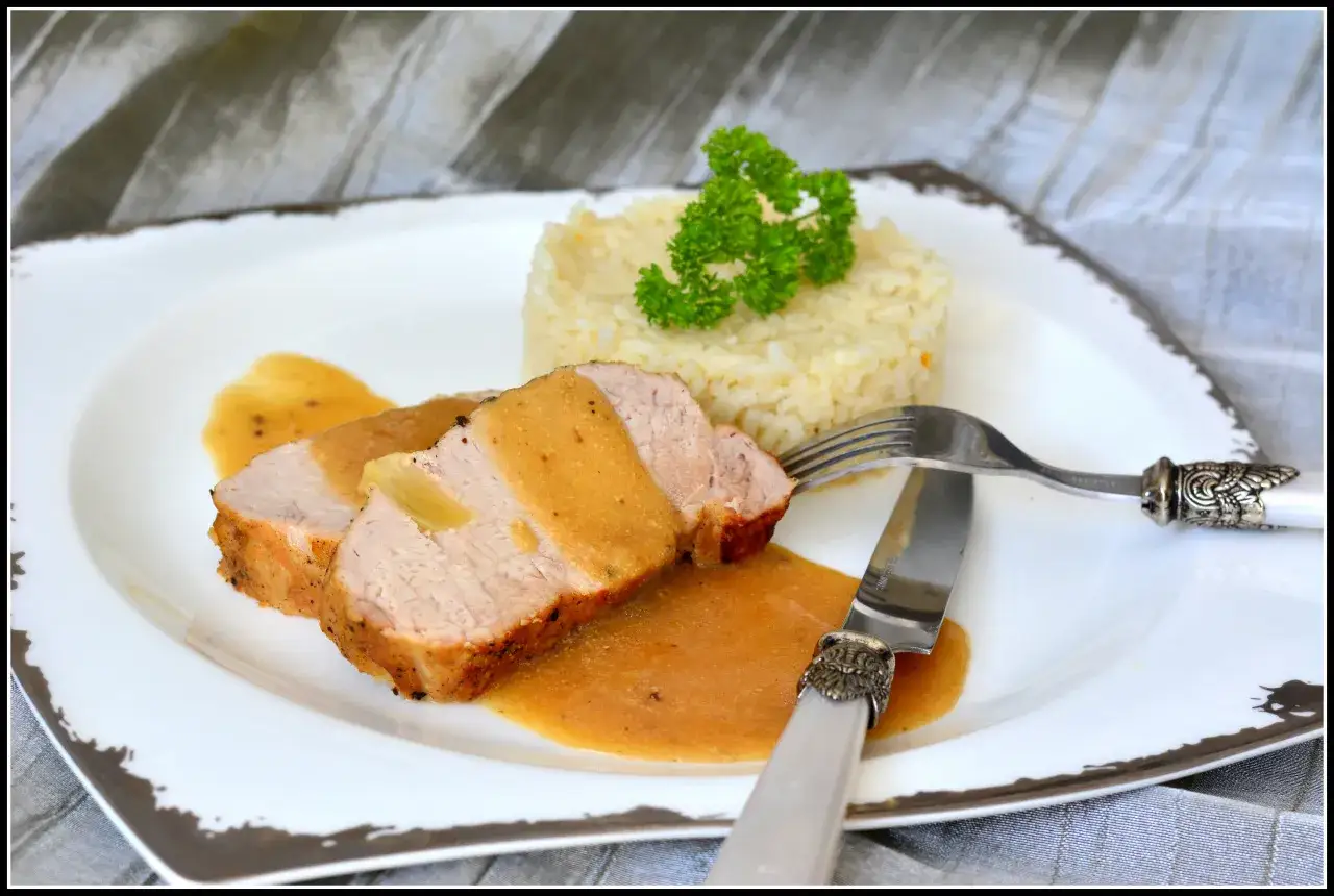 Soczysty schab w mleku i cebuli, podany z ryżem i polany aromatycznym sosem. Pyszne danie obiadowe.