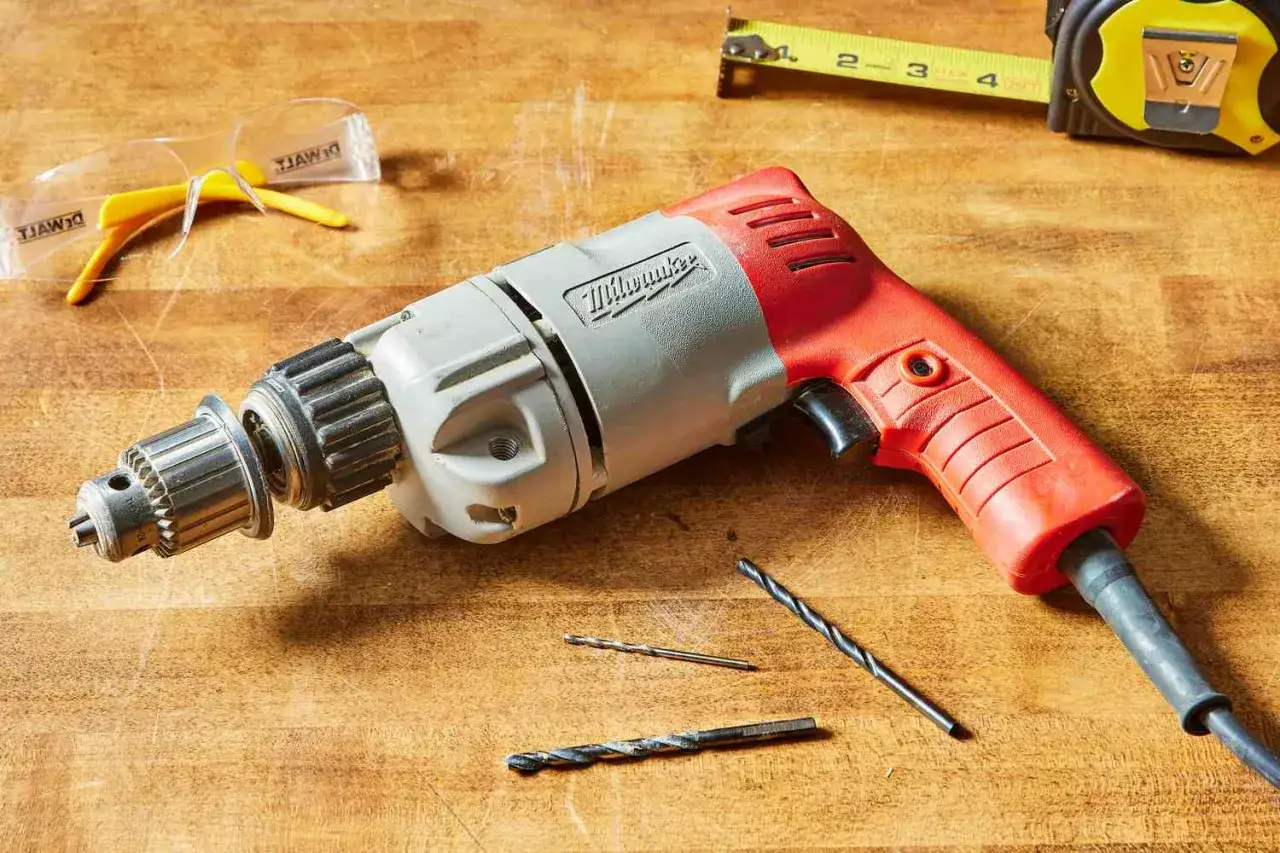 Une perceuse sert à faire des trous dans divers matériaux. Ici, une perceuse Milwaukee, des forets et des lunettes de protection sont prêts pour le travail.