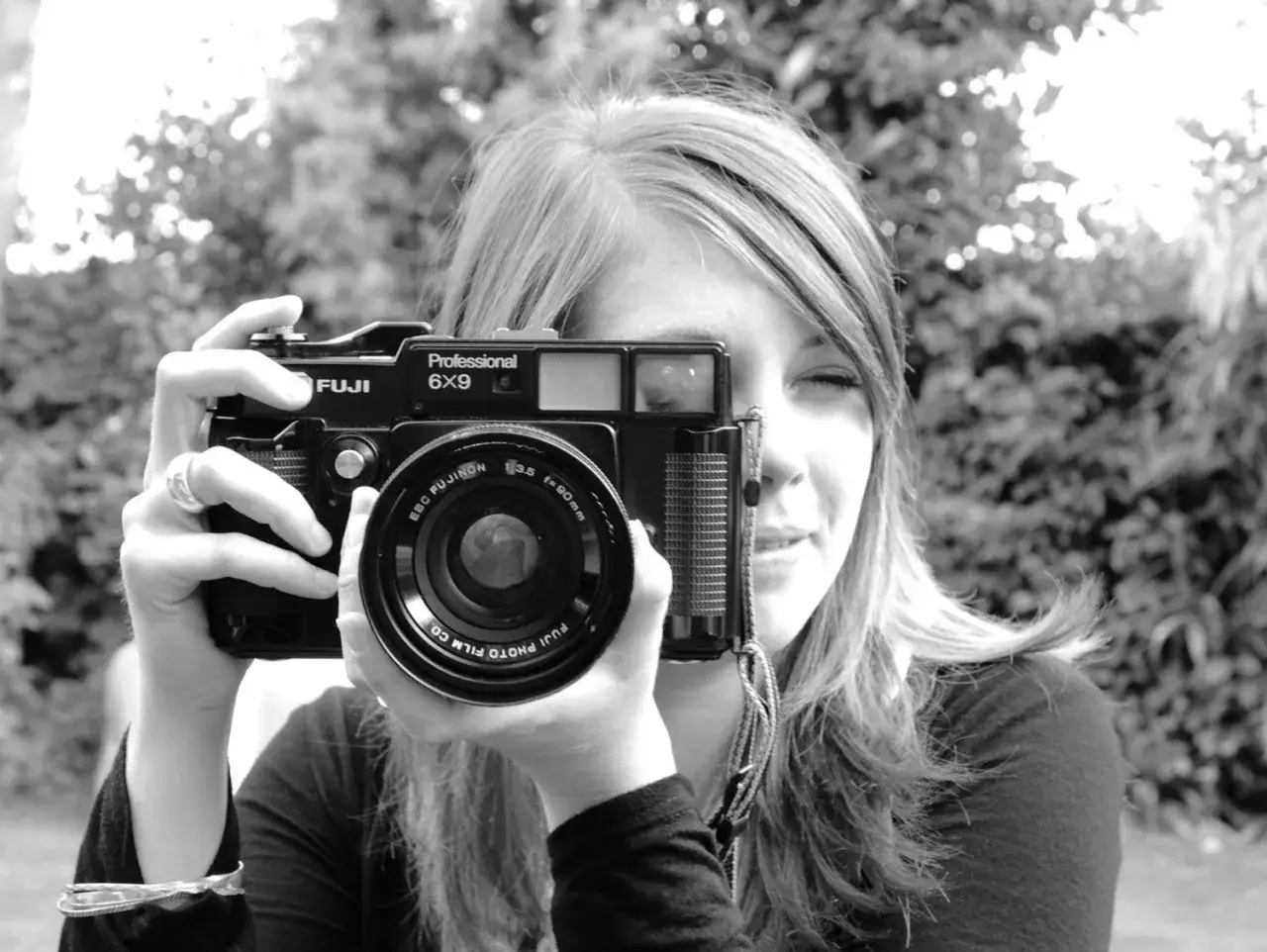 A young woman holds a Fuji Professional 6x9 medium format point and shoot camera to her eye, ready to capture a moment.