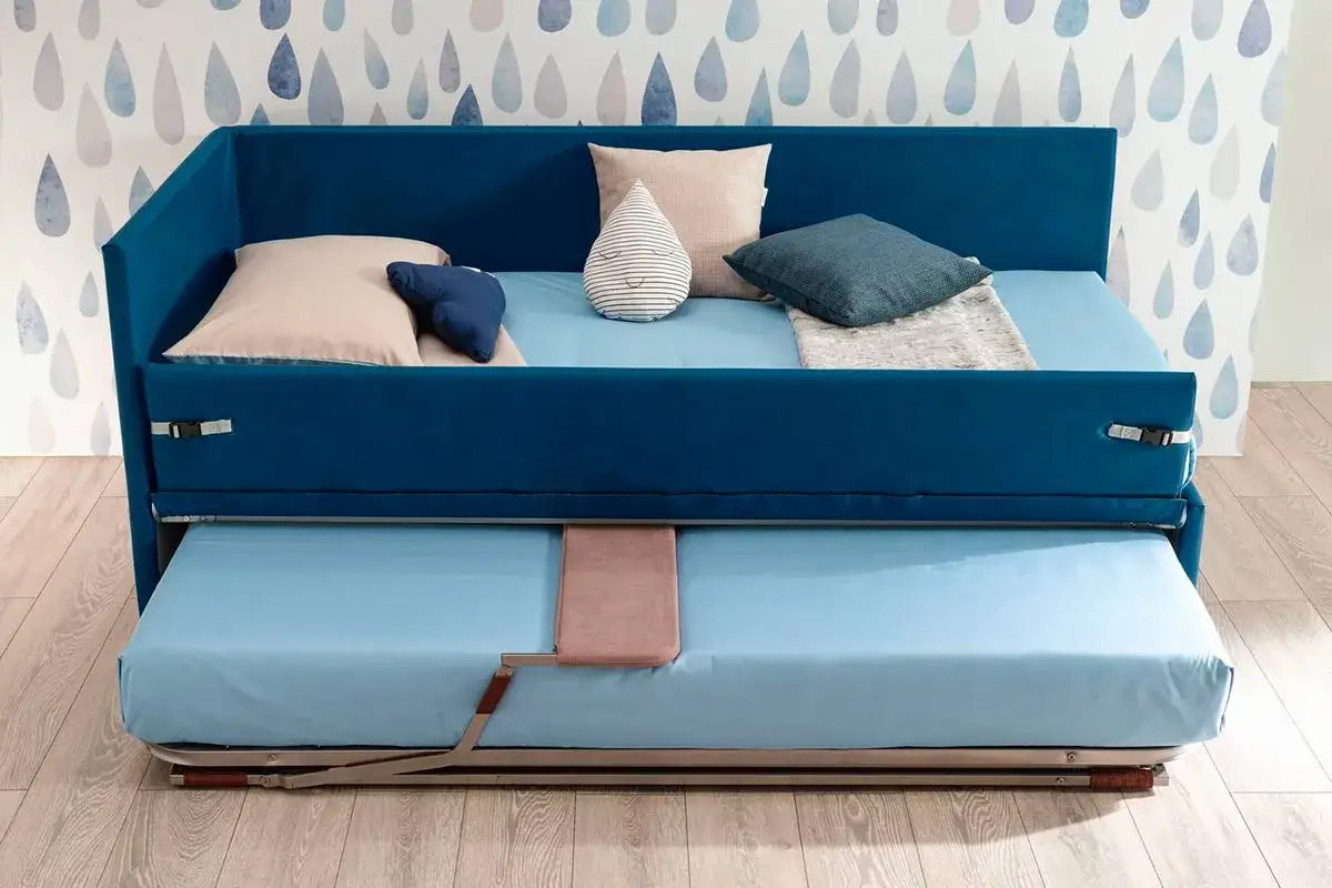 Camera studio con divano letto blu, con un secondo letto estraibile sotto. Perfetto per ospitare amici o per un riposino.