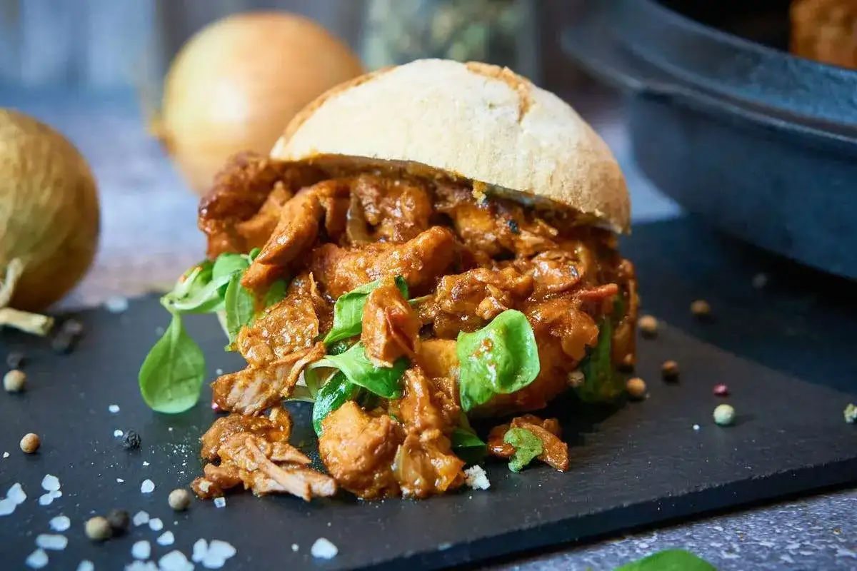Saftiges Zwiebelfleisch nach Omas Art, serviert im Br&ouml;tchen mit frischem Salat. Ein herzhafter Genuss!