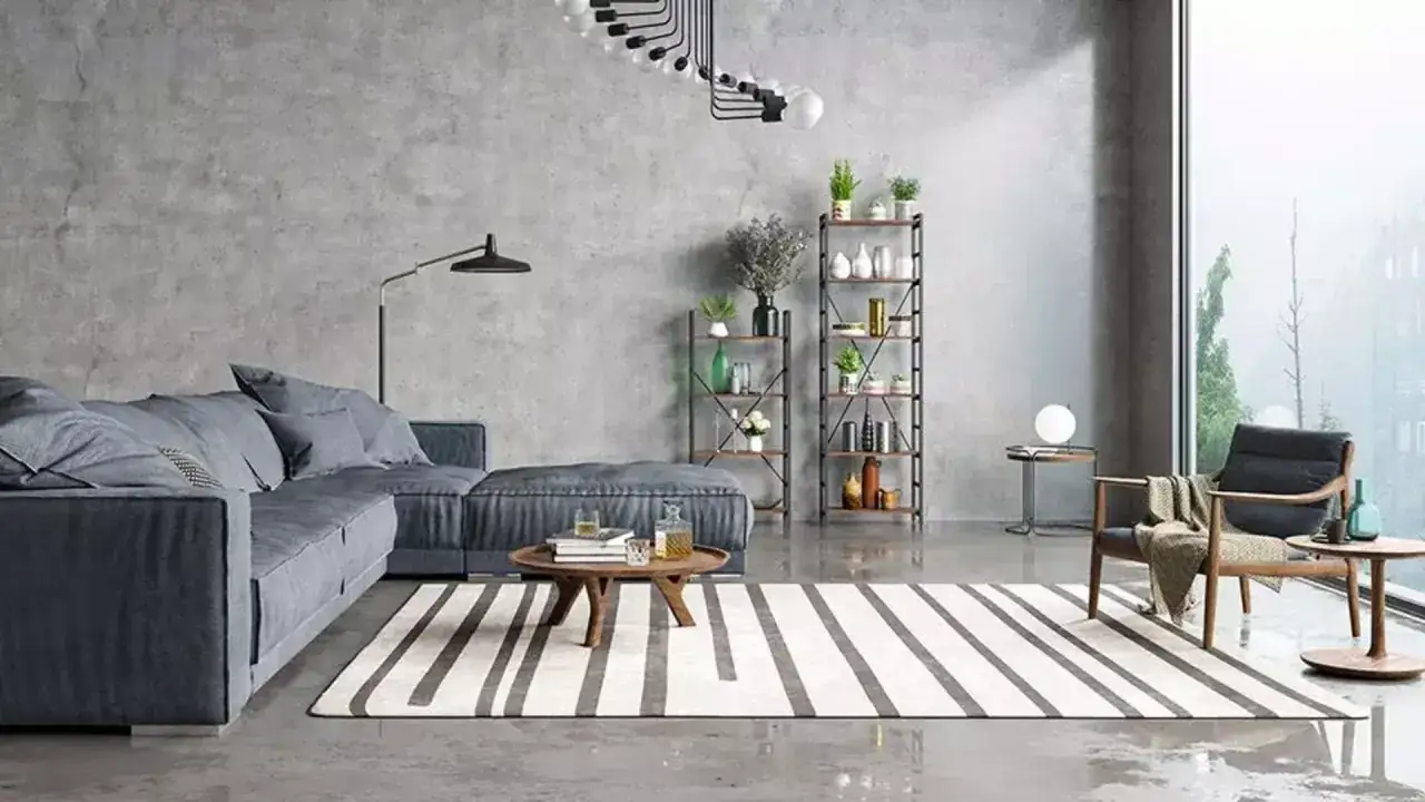 Nowoczesny salon z szarą kanapą, regałami i krzesłem. Ściany i podłoga mają surowy, industrialny **efekt betonu**.