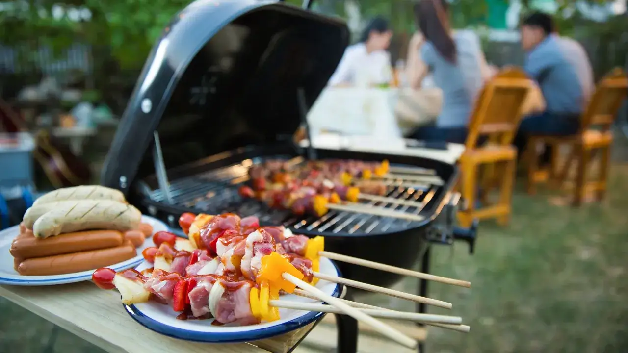 Brochettes et saucisses prêtes pour le barbecue gaz avec couvercle. La famille profite de l'été.