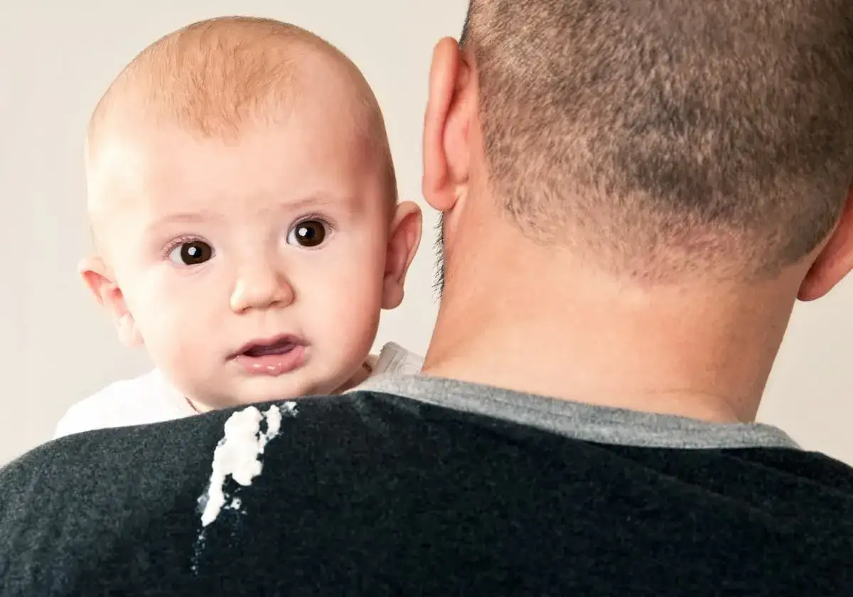 S&ouml;t bebis med stora &ouml;gon tittar fram &ouml;ver pappans axel, som har f&aring;tt lite mat p&aring; sig.