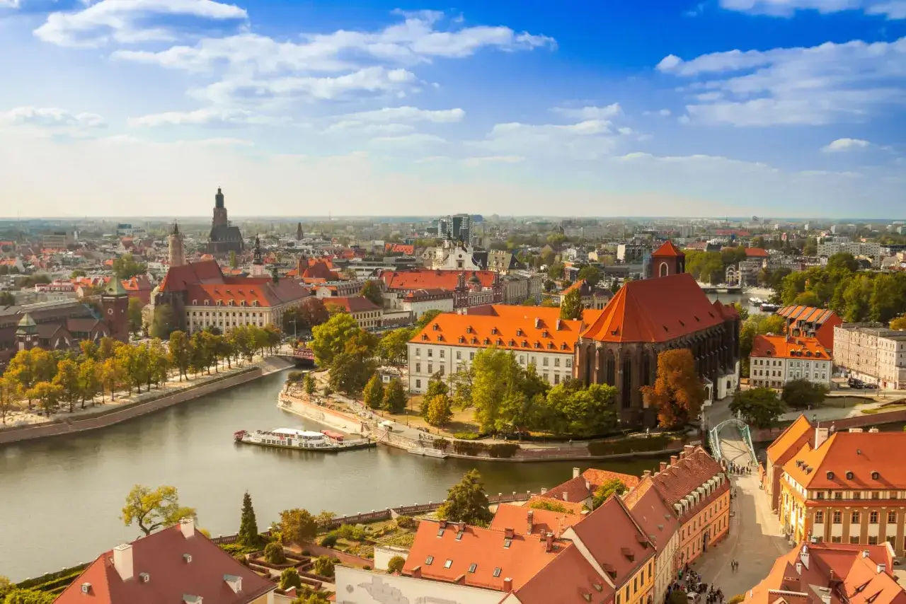 Widok na Ostrów Tumski we Wrocławiu, idealne miejsce na city break z Wrocławia. Rzeka Odra, zabytkowe kamienice i kościoły pod błękitnym niebem.