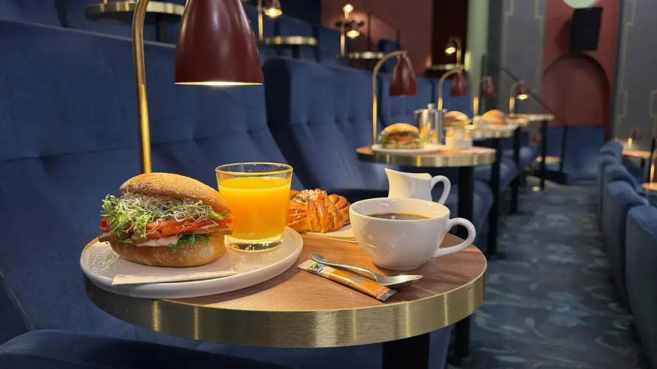 En bekv&auml;m sittplats p&aring; **Rio Bio** med en god frukostbricka: en m&auml;ttande macka, apelsinjuice, kaffe och en kanelbulle.