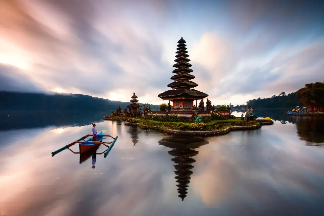 Pura Ulun Danu Bratan na Bali, jedno z najpiękniejszych miejsc na wakacje za granicą, z łodzią na spokojnym jeziorze.