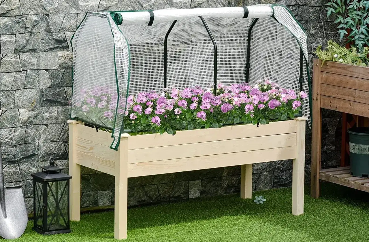Mesa de cultivo con flores moradas bajo un invernadero. Ideal para ver qu&eacute; se puede plantar en una mesa de cultivo y proteger tus plantas.