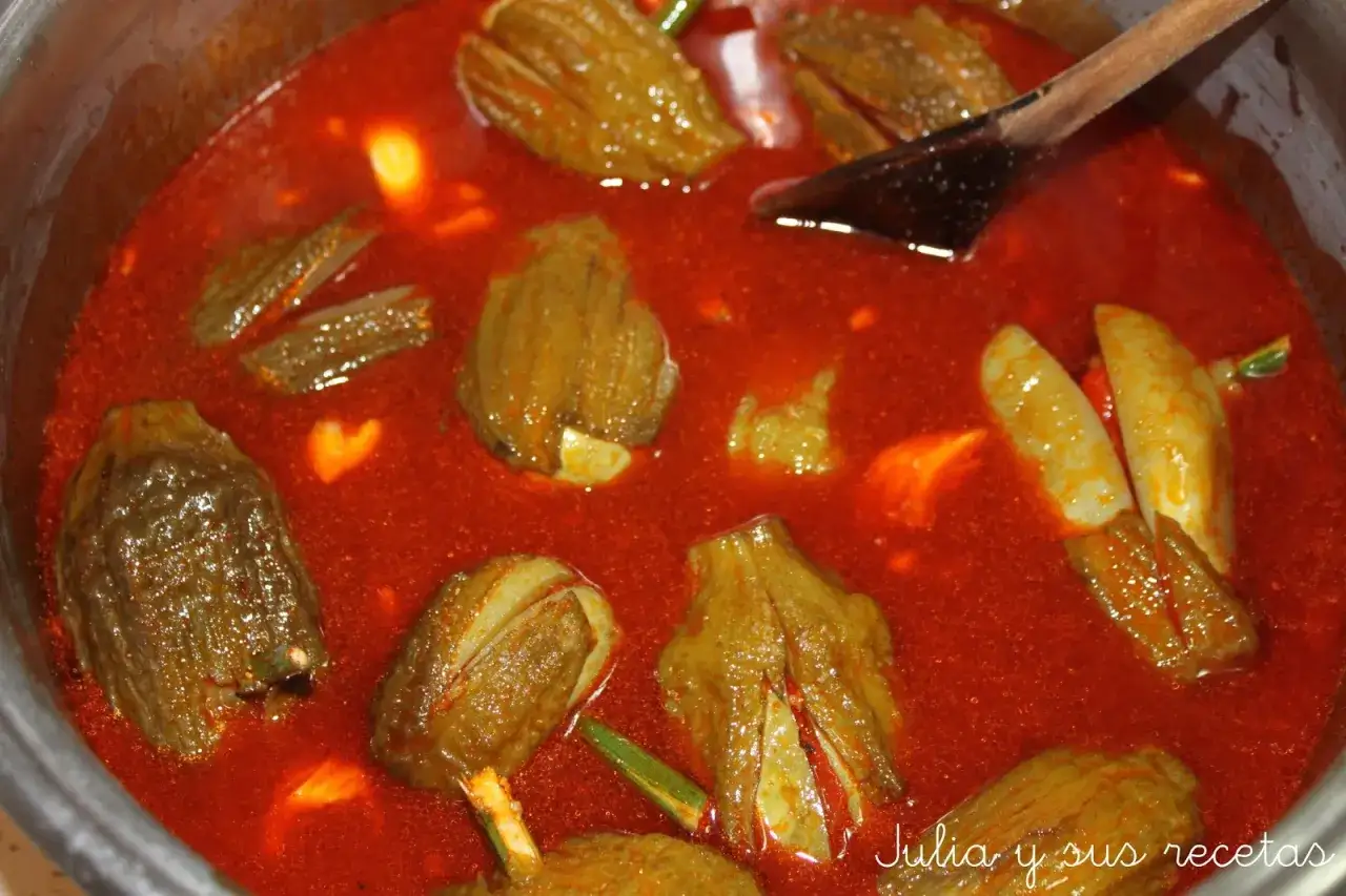 Berenjenas en vinagre de la abuela, cocinándose en una olla con salsa roja. Un plato casero lleno de sabor.