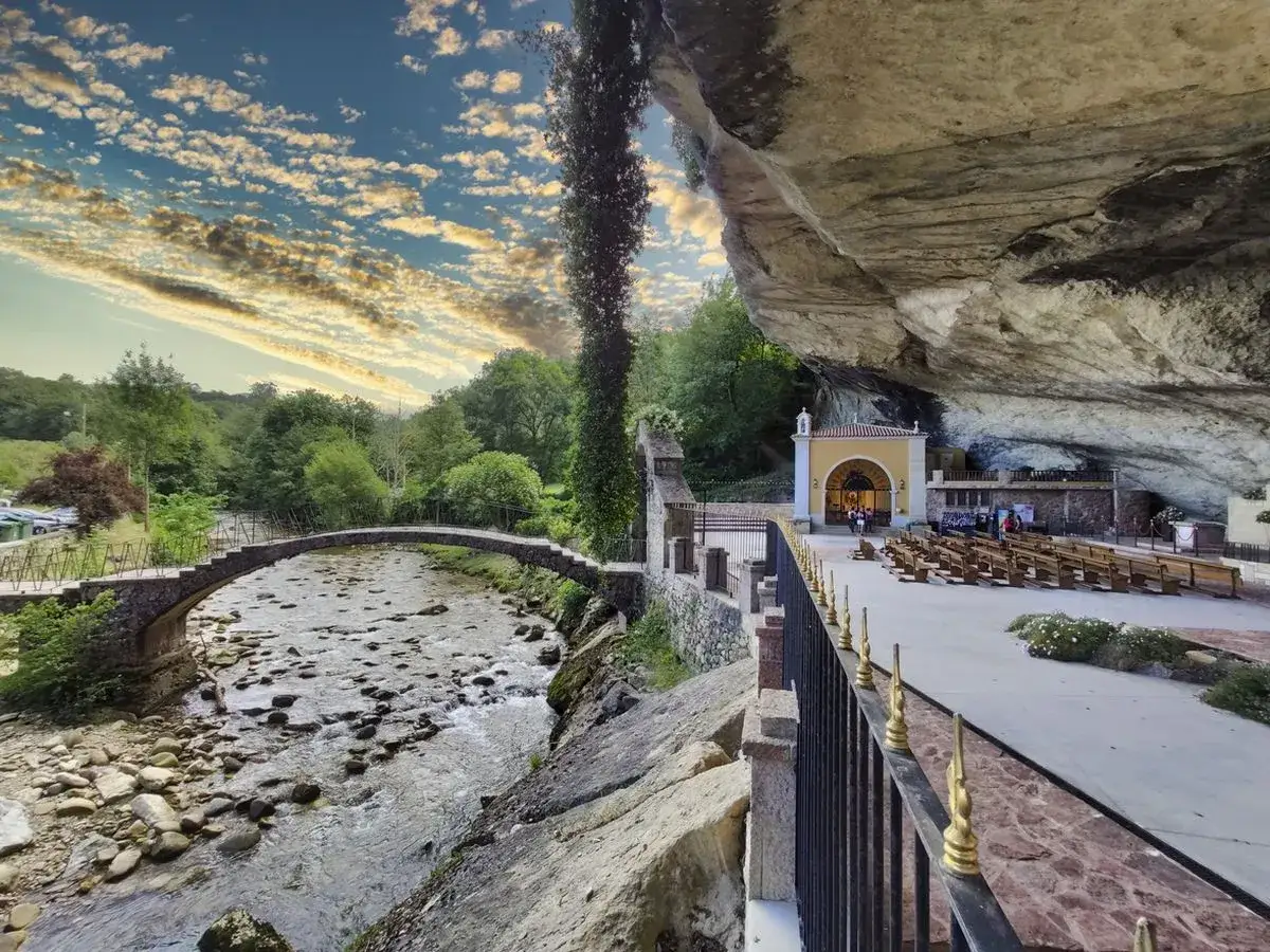 Capilla bajo una roca, con un puente de piedra sobre un río. Un lugar que parece sacado de una película, como si fuera el escenario de