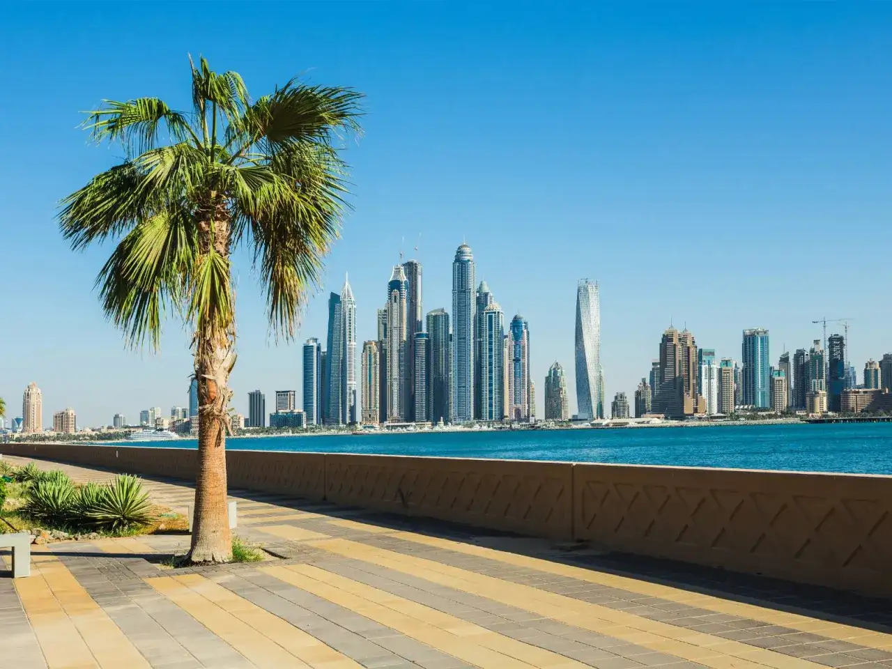 Dubaj pogoda luty: słonecznie, ciepło, idealnie na spacer po promenadzie z palmą i widokiem na drapacze chmur.