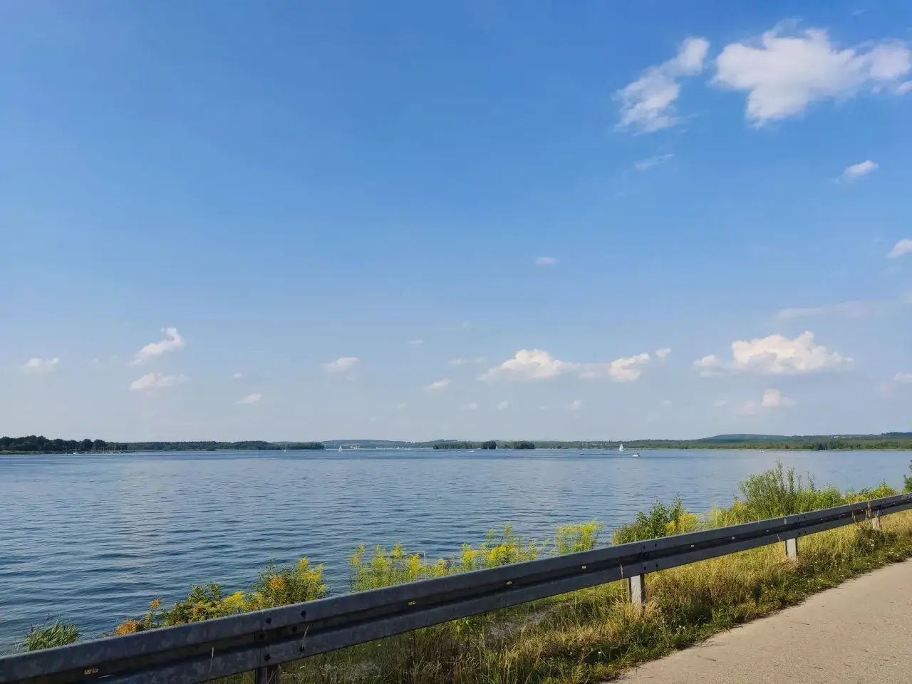 Piękny dzień nad Pogorią 4. Błękitne niebo, spokojna woda i żagl&oacute;wki na horyzoncie.