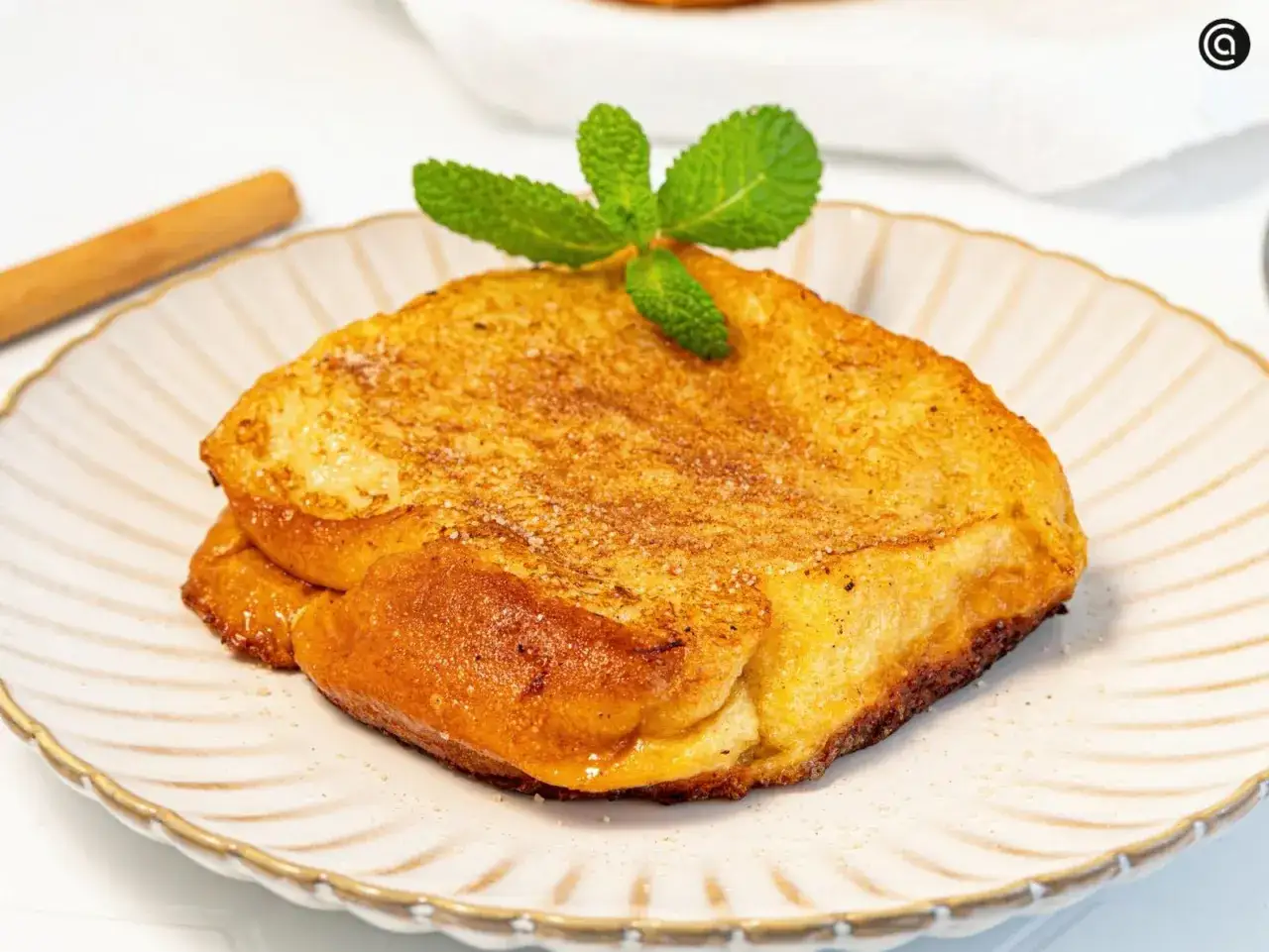 Torrijas de horchata doradas y crujientes, espolvoreadas con azúcar y canela, coronadas con menta fresca.