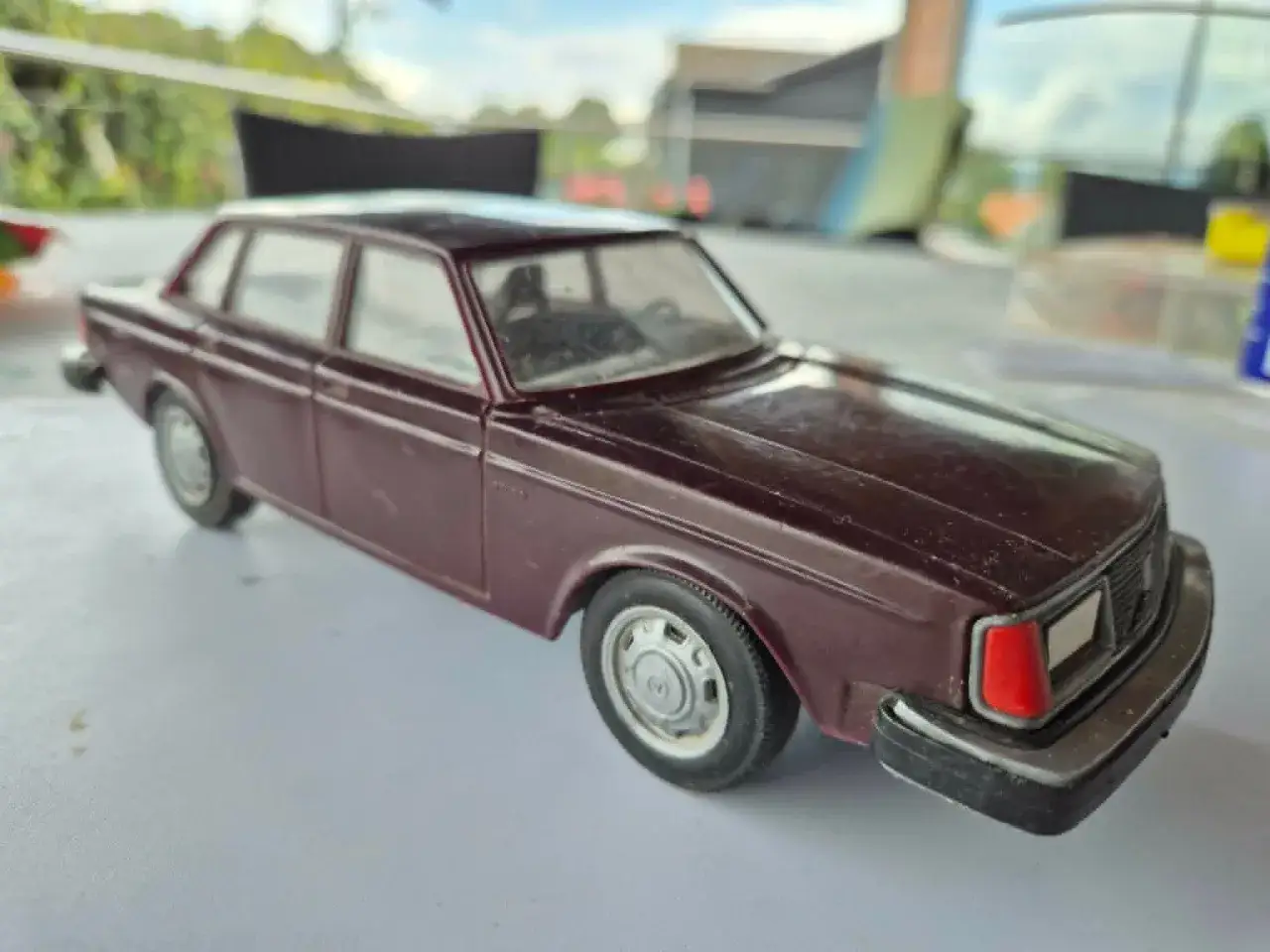 En mörkröd leksaksbil, en klassisk Volvo 244 DLS, står på ett bord.